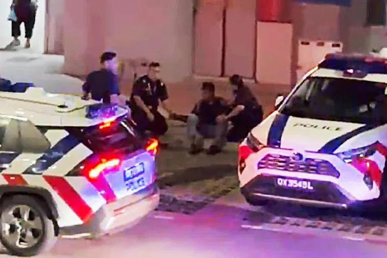 男子坐在地上，三名警员围在身边。（受访者提供）
