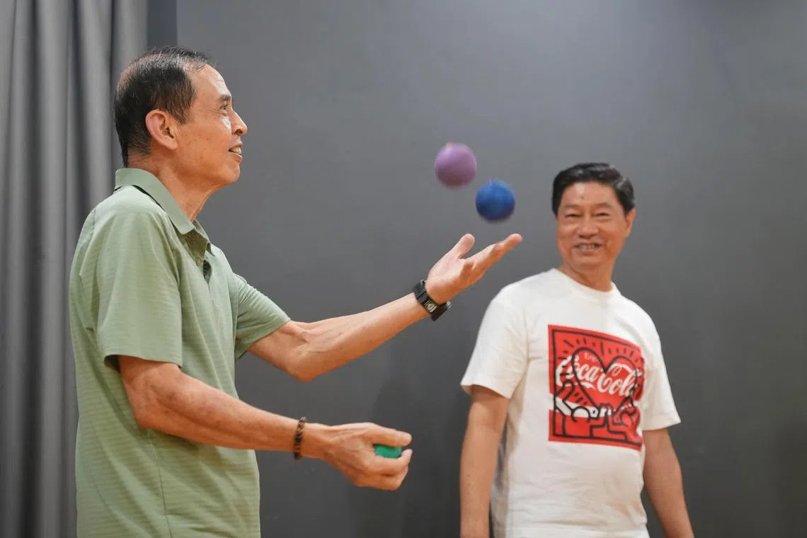 73岁的吕联义（左）和62岁的陈国利是其中参与“黄金绅士马戏团”（Senior Gentlemen’s Circus）试点活动的两名安哥，他们开心地学习着抛接球。（谢智扬摄）