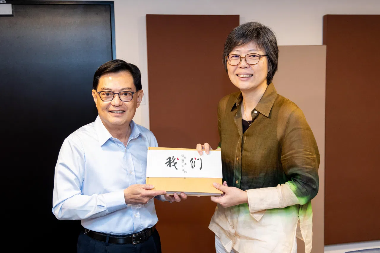 副总理兼经济政策统筹部长王瑞杰（左）前来报业中心录制《还是硬道理吗？》播客系列，新报业媒体信托华文媒体集团社长李慧玲赠送《联合早报》百年报庆之作《我们——联合早报口述历史》。（关俊威摄）