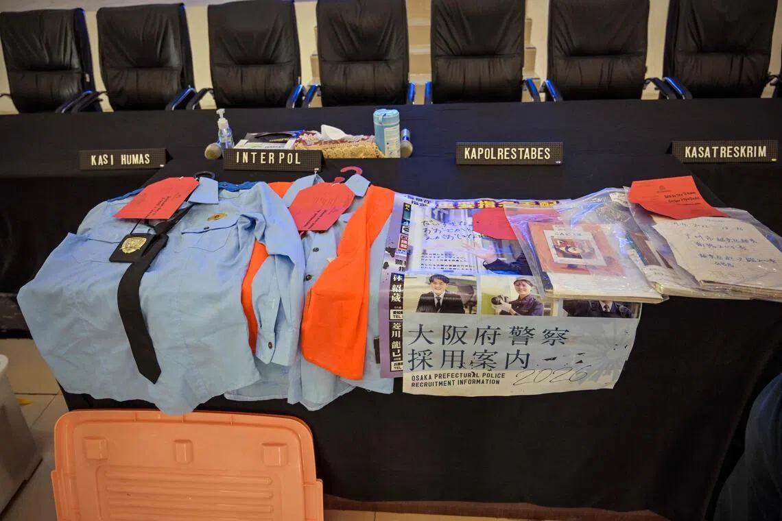 印尼警方在记者会上展示起获的诈骗工具，包括仿制的日本警服及一些文件。（法新社）
