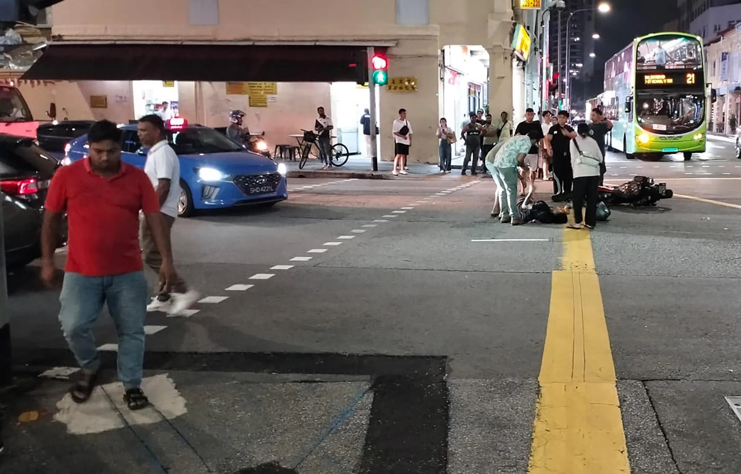 电单车骑士腿部受伤倒在地上，周围有热心人士上前帮忙。（受访者提供）