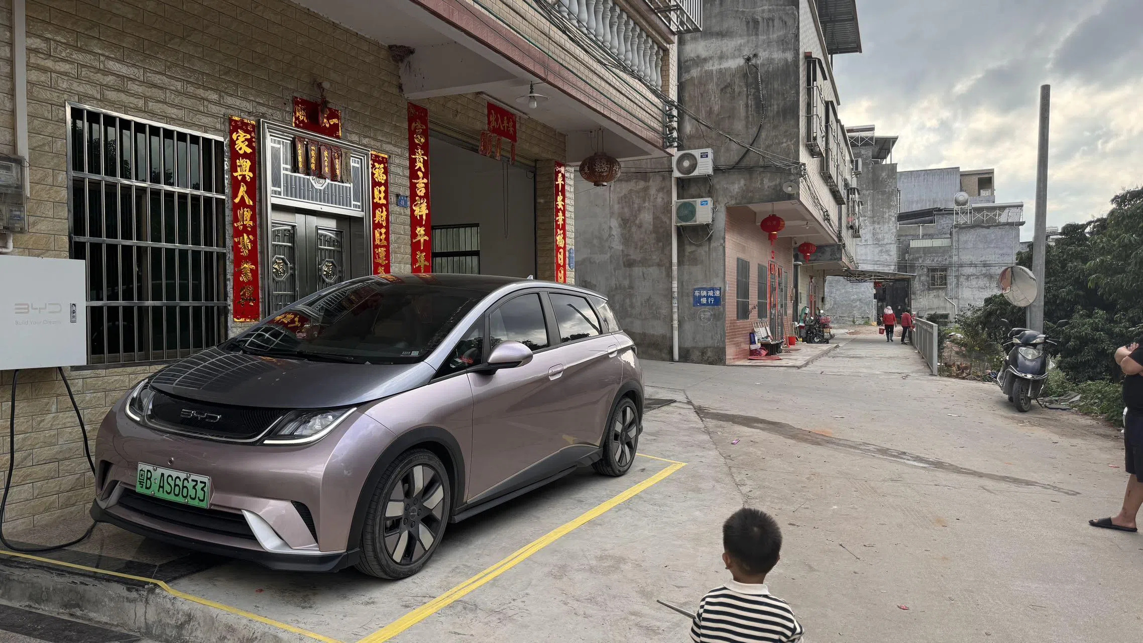 深圳酒吧从业者邓浩文2021年买了一辆比亚迪“海豚”电动汽车。他在充电桩充电每度电0.4元，平均每100公里只花10元。（受访者提供）