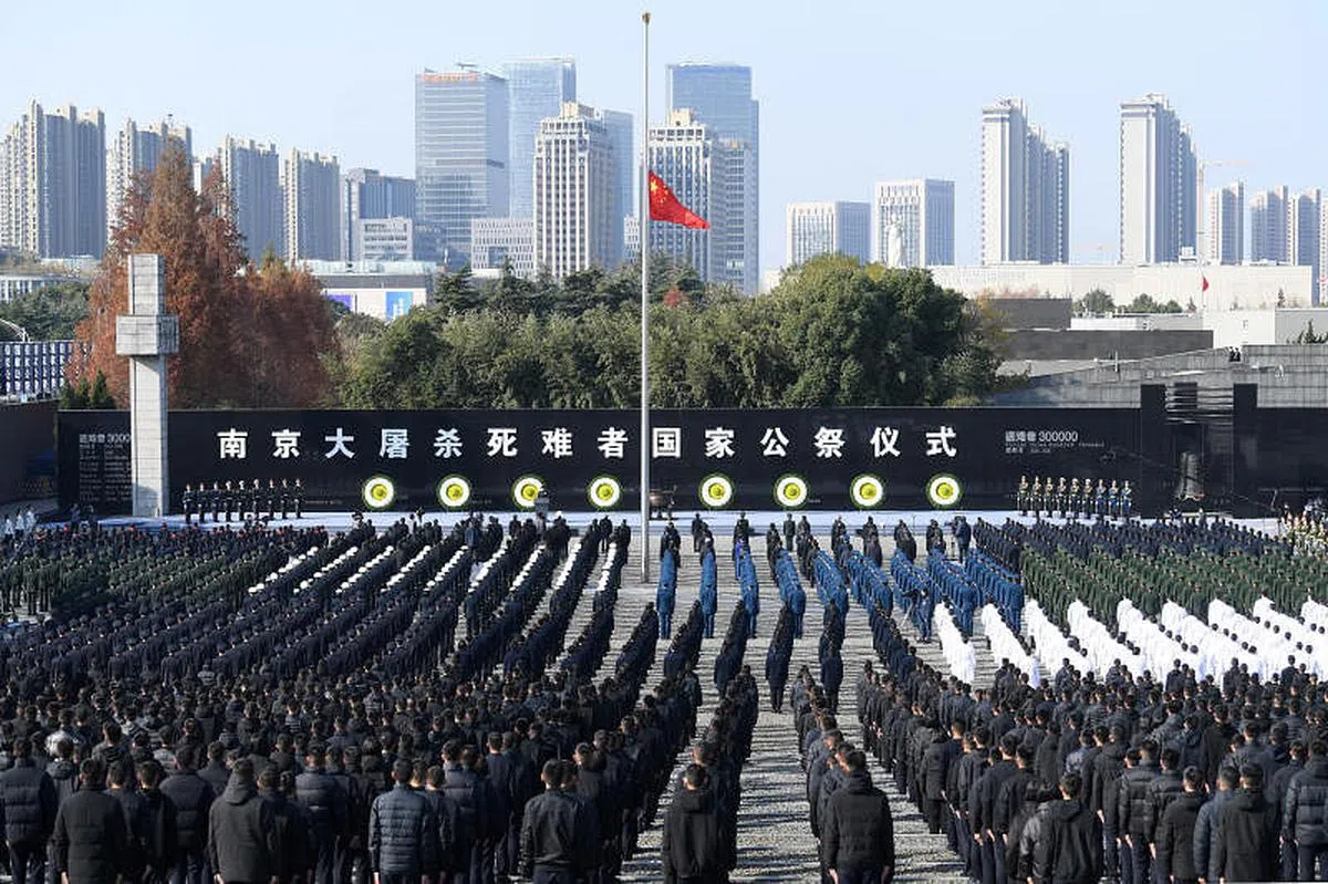 公祭仪式现场国旗下半旗，约3000名各界代表胸前佩戴白花参加。（中新社）
