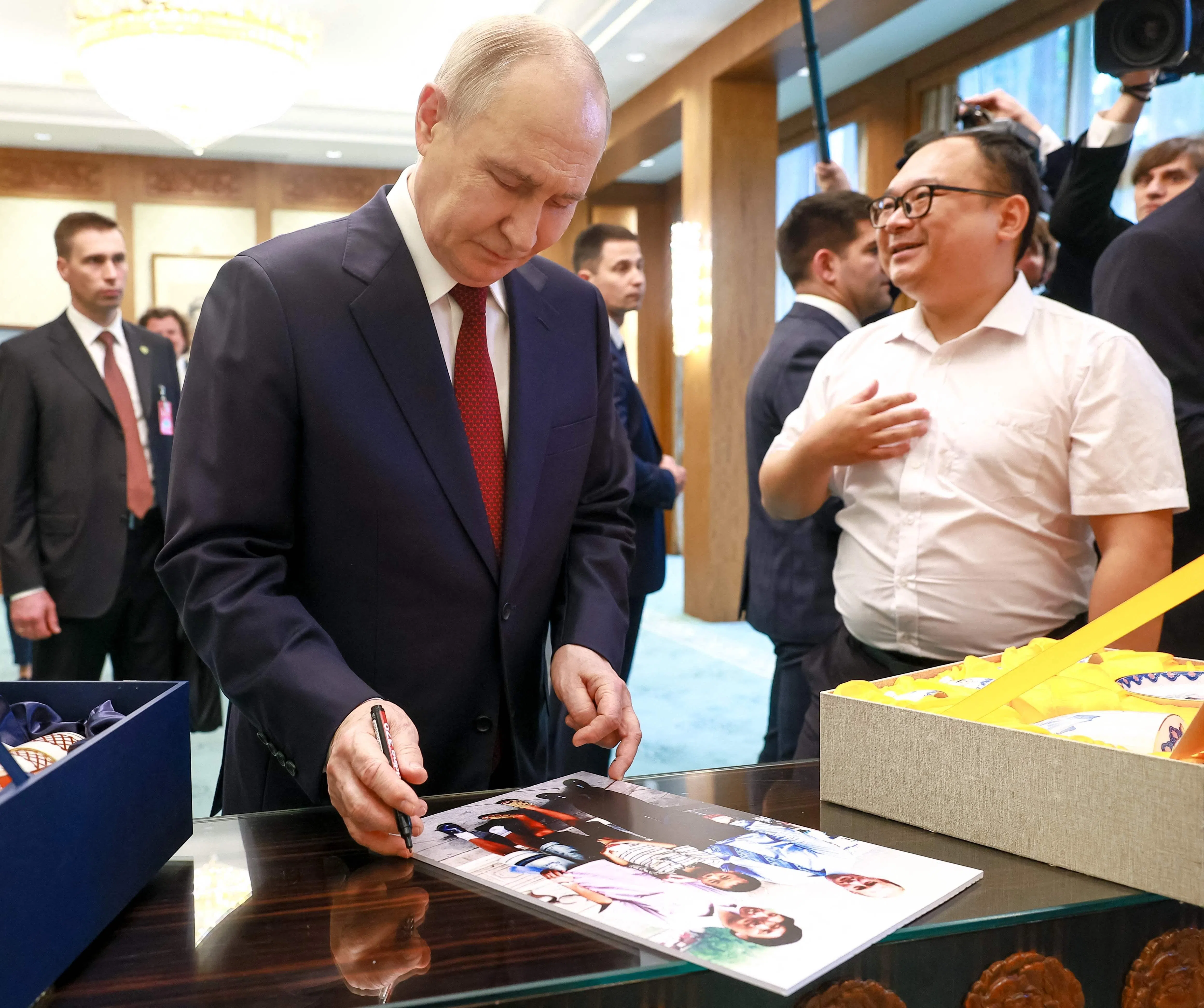 俄罗斯总统普京星期三（5月20日）在钓鱼台国宾馆与26年前访华时在公园偶遇的中国男孩彭湃重逢，除了互赠礼物，他也在一张当年所拍的合影上为彭湃签名留念。（法新社）