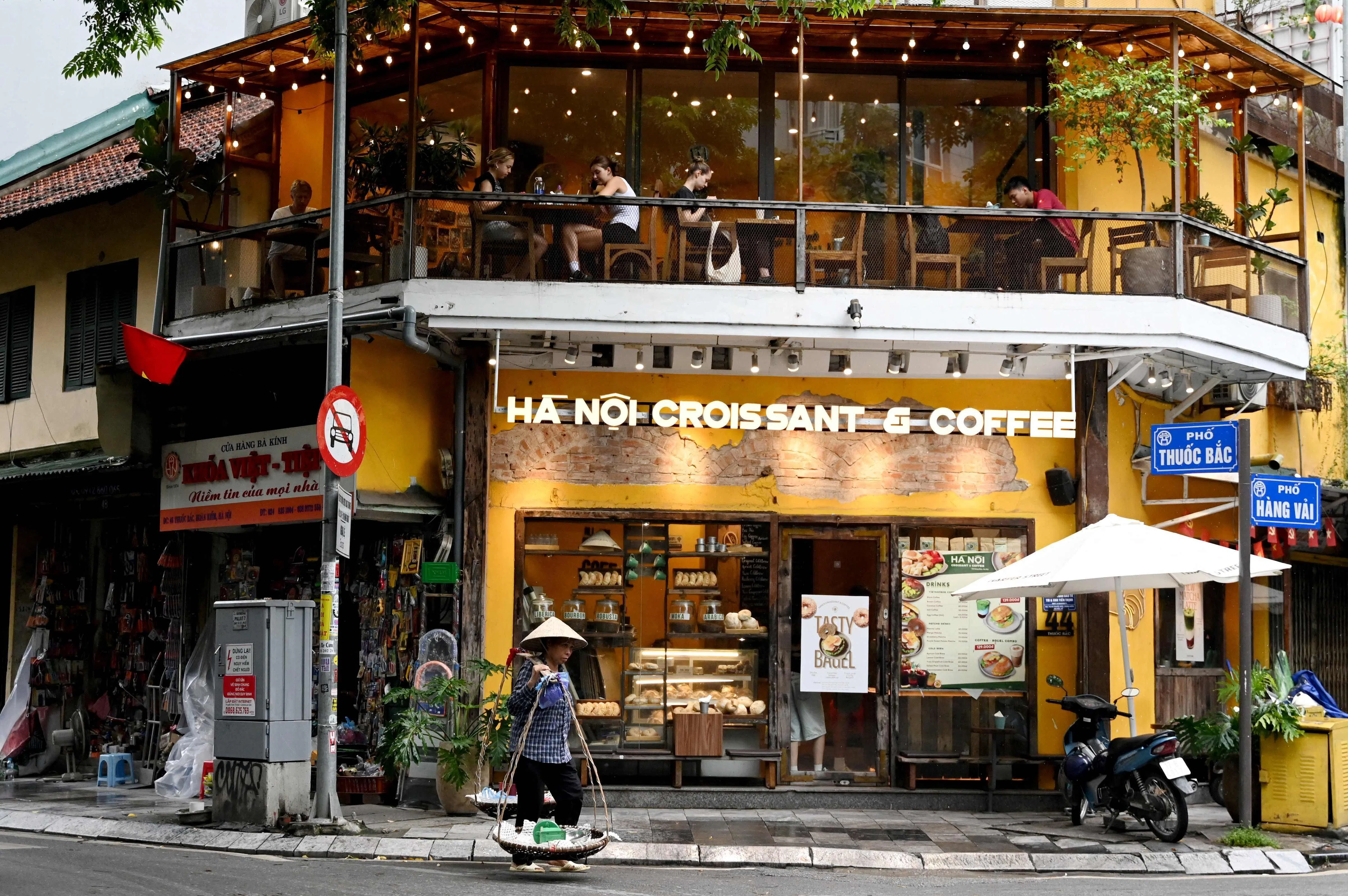 8月21日，一名街头小贩走过越南河内的一家面包咖啡店。咖啡是越南代表性美食之一。（法新社）