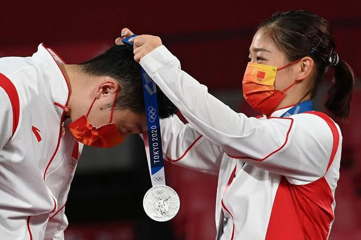 中国乒乓选手刘诗雯（右）为队友许昕戴上奥运会混双银牌。中国队在26日的决赛中，惜败日本组合，与金牌失之交臂。（法新社）