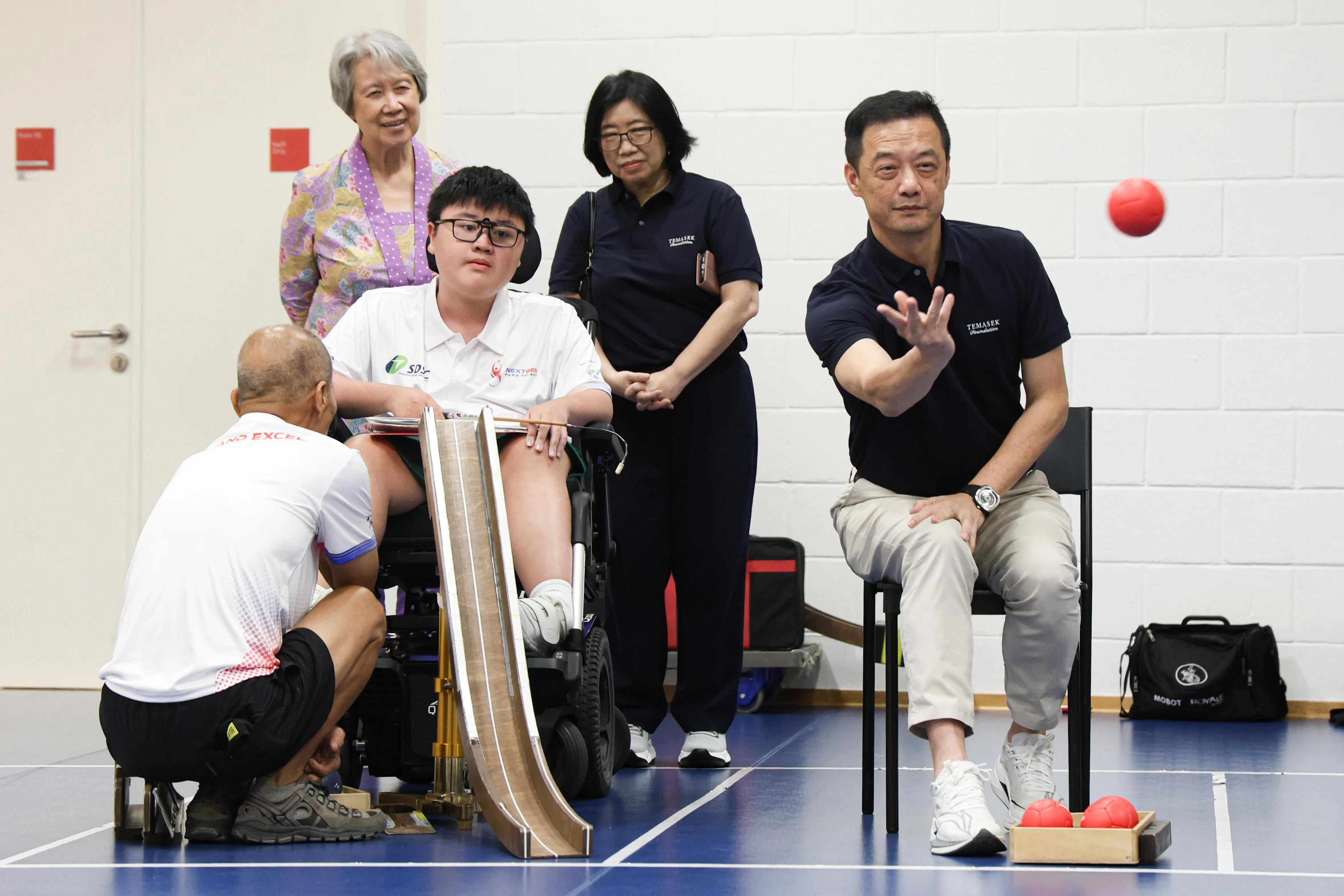 淡马锡基金会执行董事兼首席执行长黄文雄（右一）当天尝试硬地滚球。淡马锡信托基金会主席、 新加坡残疾体育理事会赞助人何晶（最后排左一）是当天的嘉宾之一。（关俊威摄）