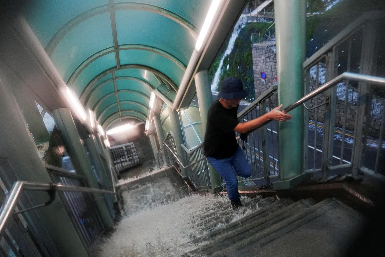 香港8月5日暴雨期间，雨水有如湍急的溪流冲下行人天桥台阶，行人得小心翼翼涉水而上。（路透社）