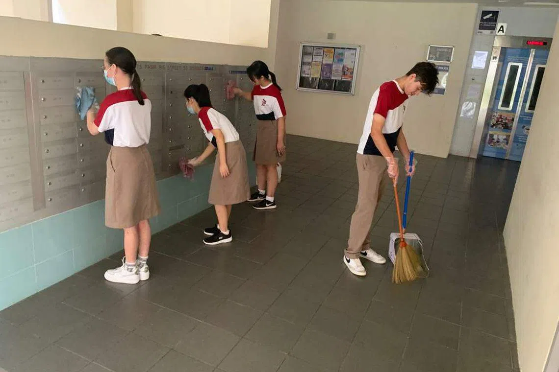 学生忙着擦拭组屋区的邮箱。（淡滨尼美廉初级学院提供）