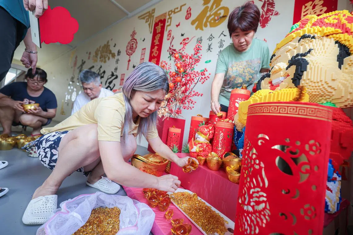 最初只是简单地摆几盆桔子树，后来每年的装饰逐渐变得更精致。高秀菁（黄色上衣）去年特意网购了财神爷造型的乐高，与邻居们分工组装完成。“直接买现成的财神爷装饰没意思，想挑战自己动手。大家一起布置，除了好玩，还能联络感情，很有意思。”据说，还有淡滨尼居民特别前来欣赏并打卡。（李冠卫摄）
