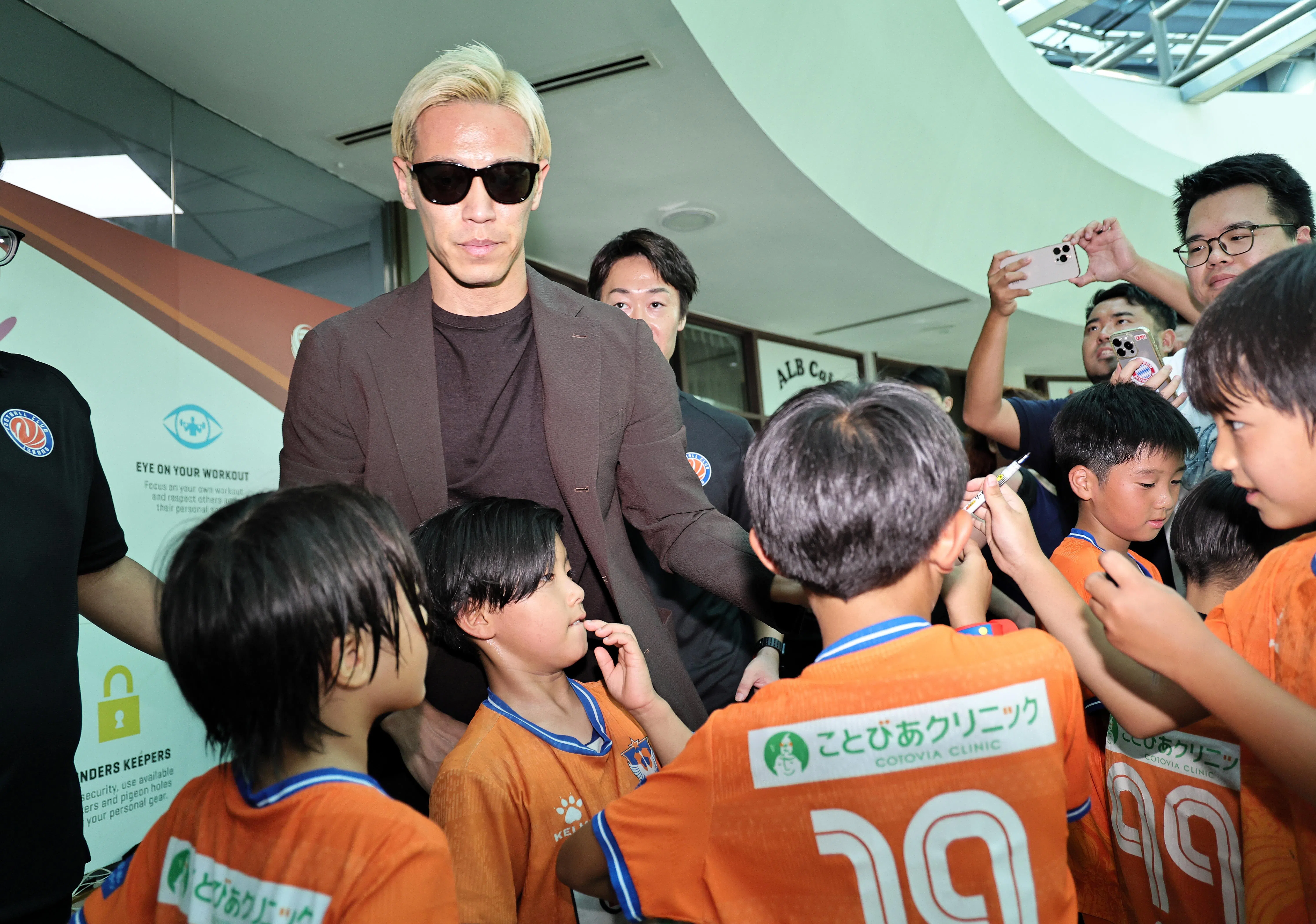 结束记者会后，本田圭佑（戴墨镜者）给守候在外面的小球员们一一签名。（海峡时报）