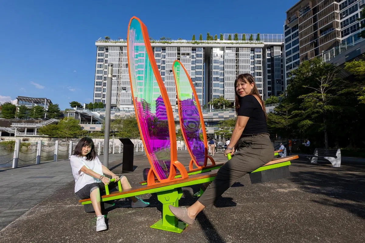 艺术工作者郭晓慧（左）和林素贤坐金皮蕨跷跷板，玩自己的创作。（张思庆摄）