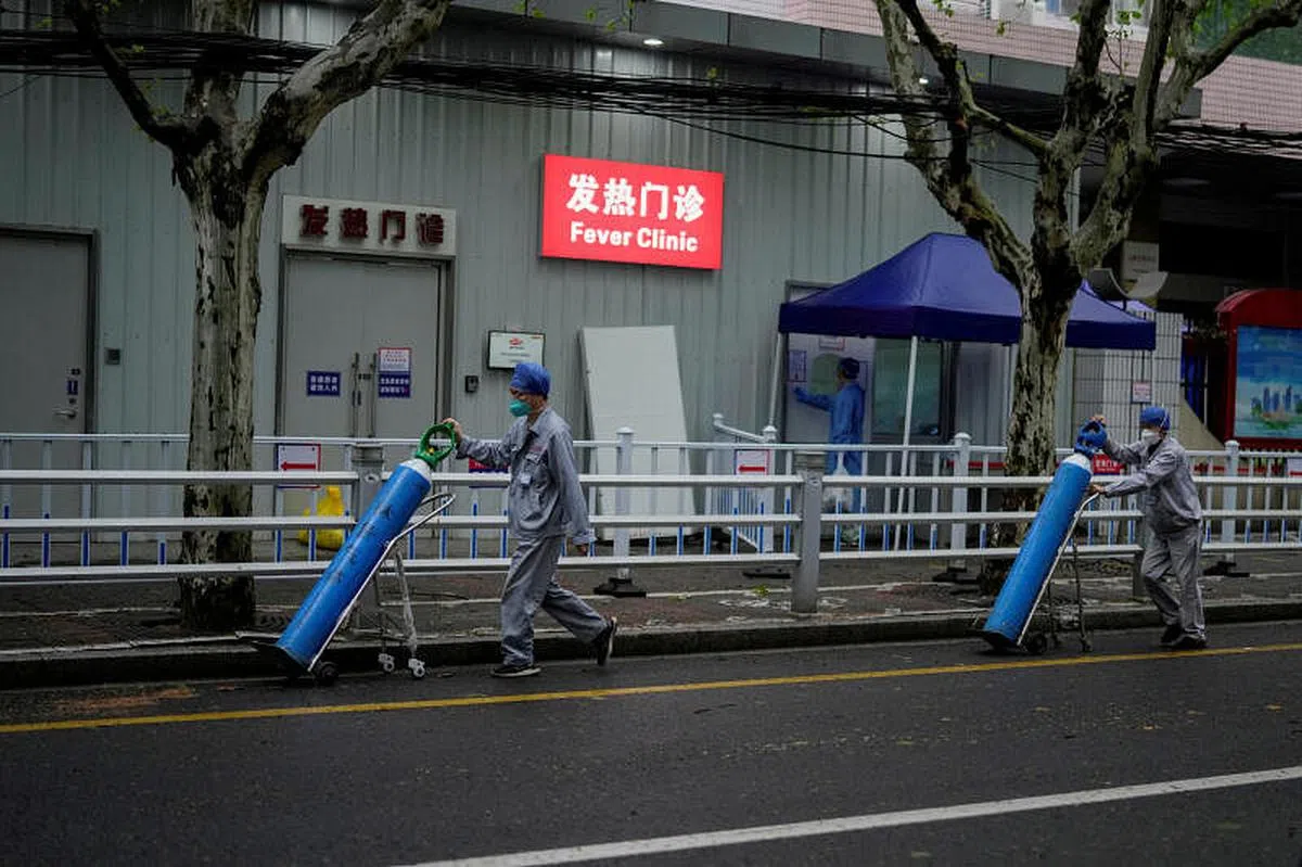 4月14日，在上海一家诊所外，两名工人正运送氧气瓶。（路透社） 