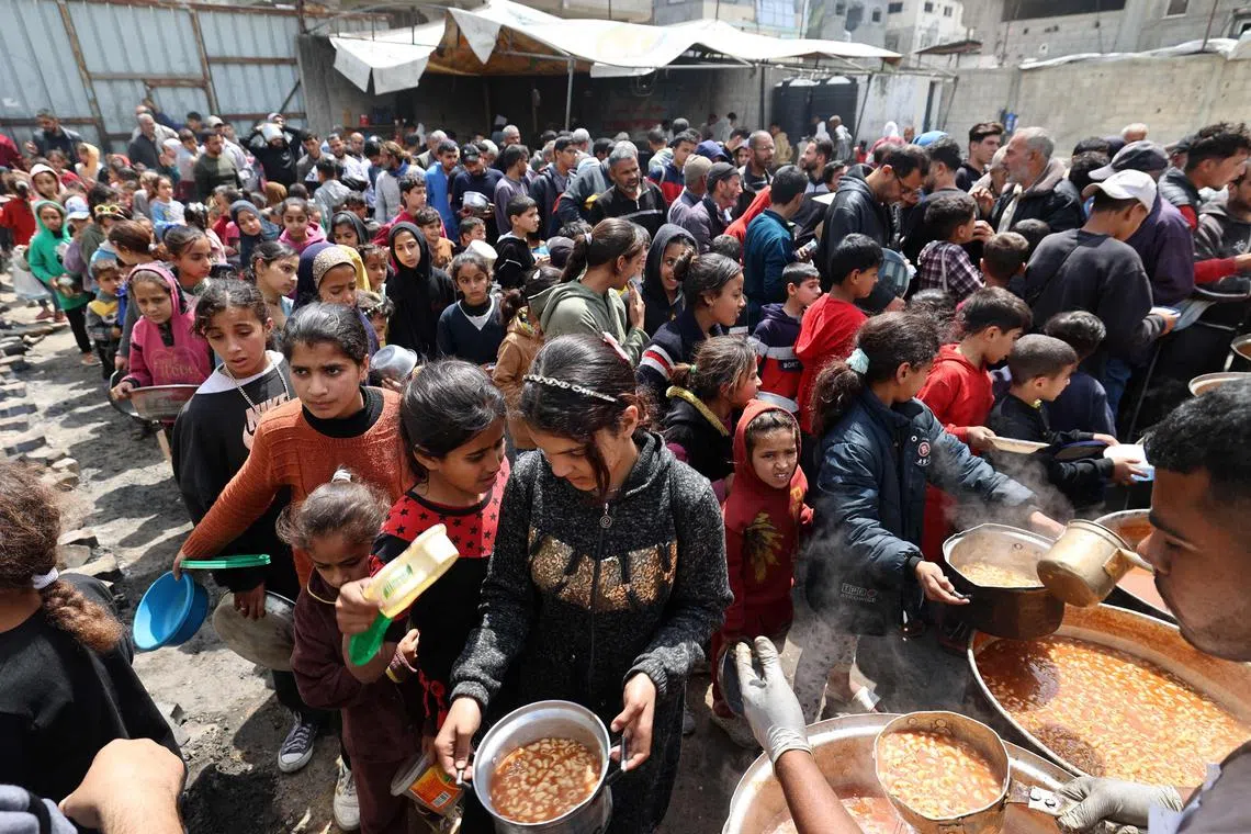 4月12日，巴勒斯坦人在加沙地带中部努塞拉特难民营的食物分发点前等待领取热餐。（法新社）