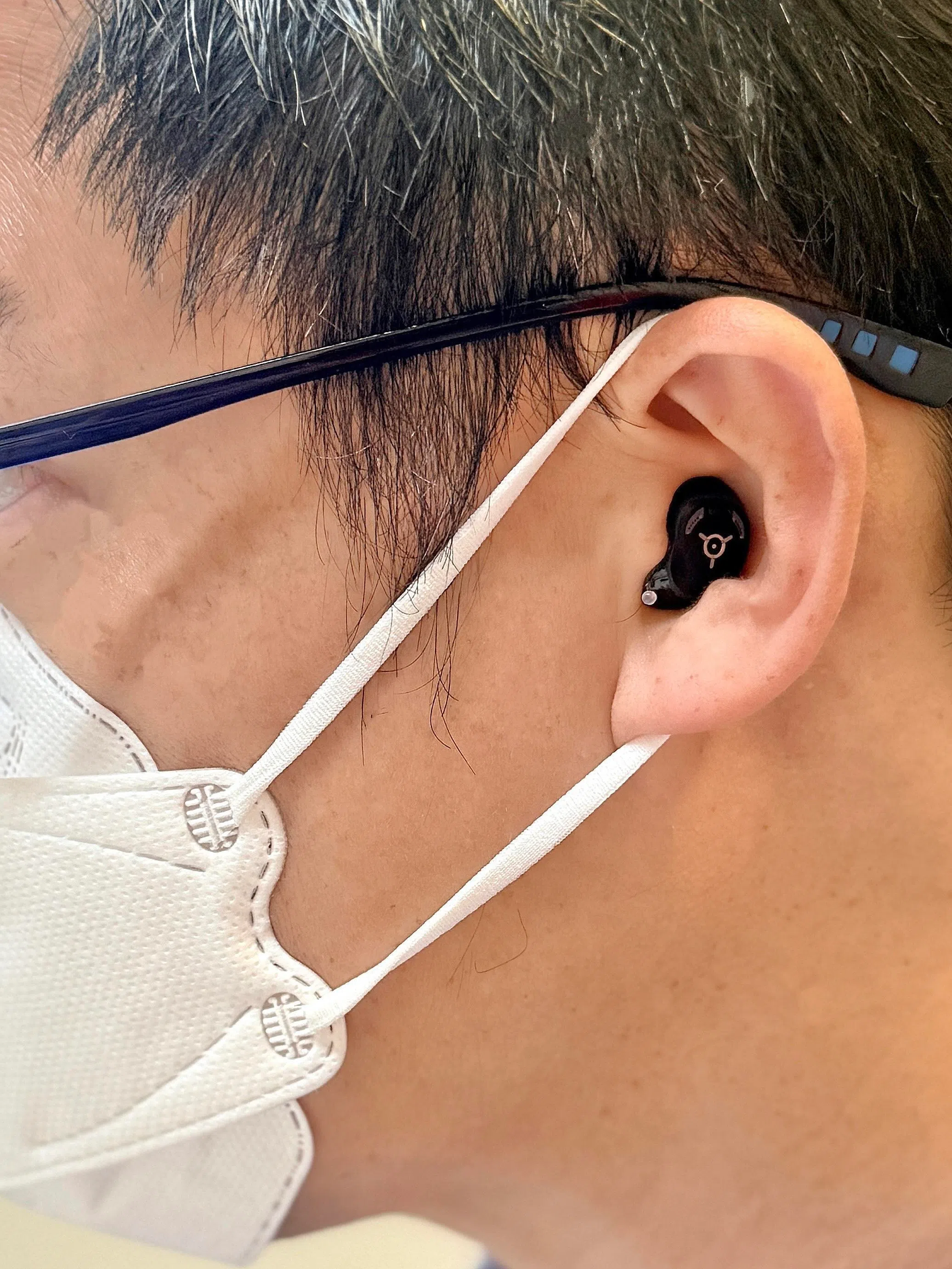 现代定制助听器小巧隐蔽，支持AI和蓝牙，戴眼镜或口罩也方便。（受访者提供）
