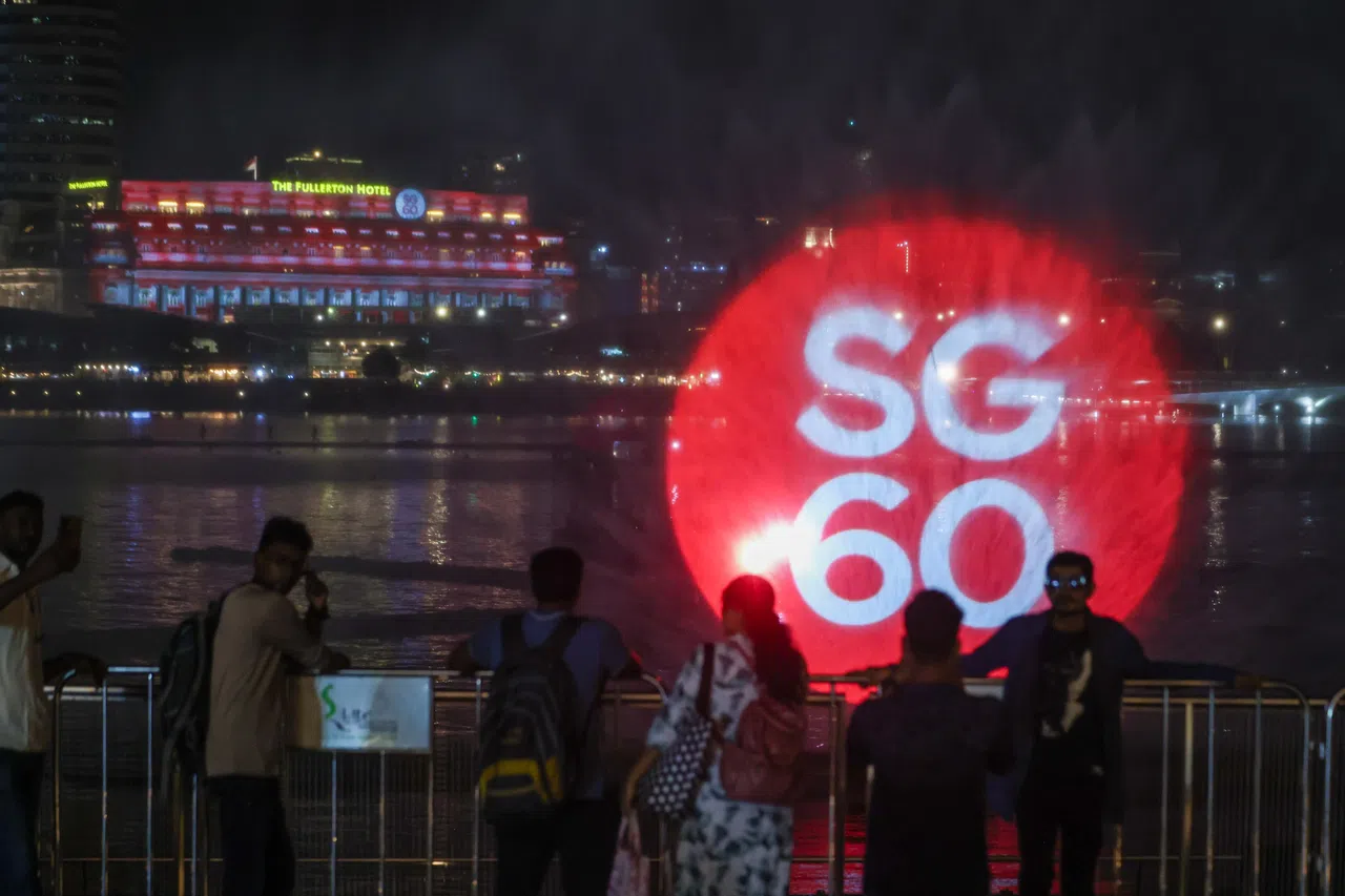 跨年烟花表演结束后，火红色的SG60标志也投映在富丽敦酒店外墙和滨海湾金沙活动广场前的水幕上。（白艳琳摄）