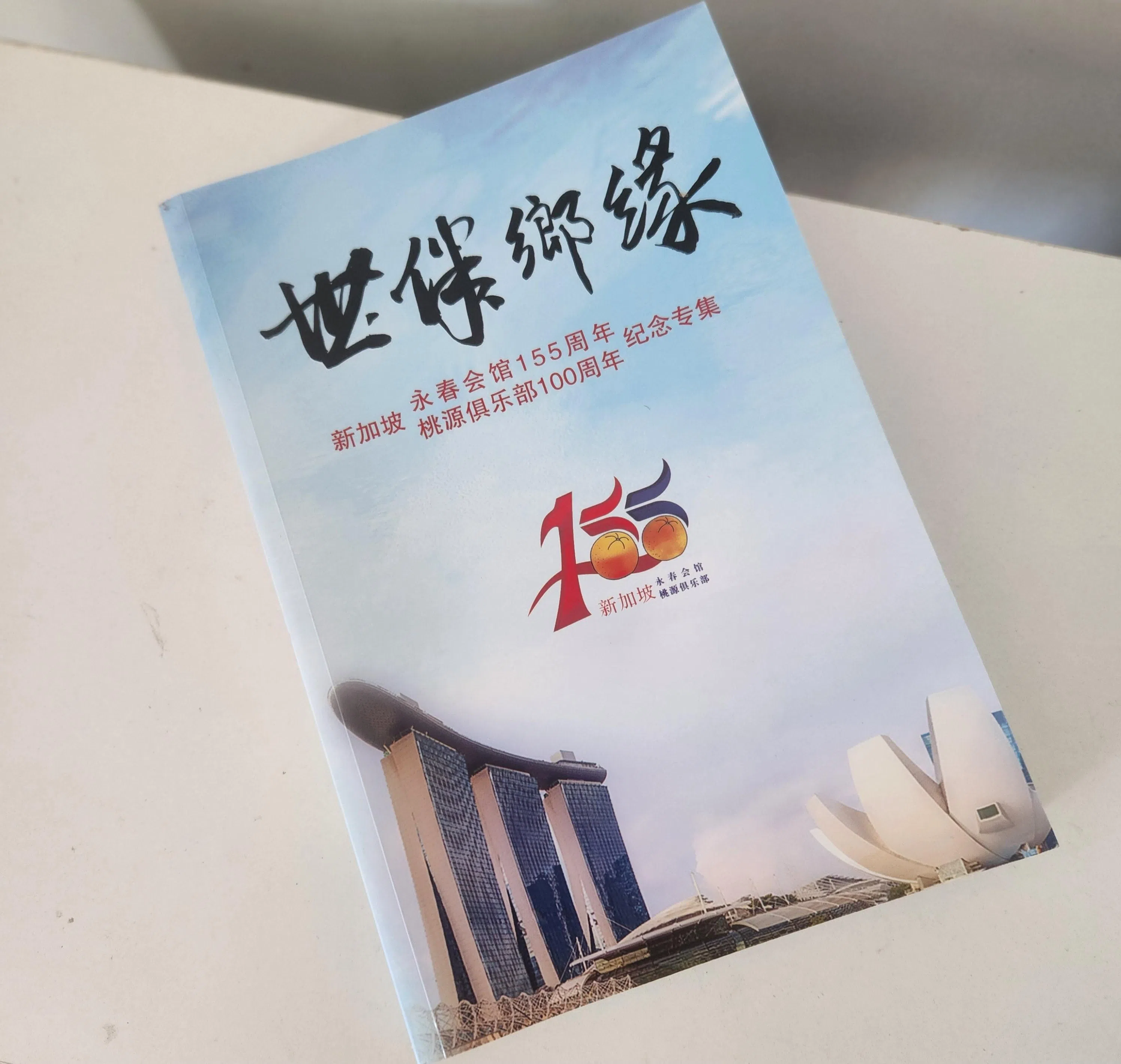 《世伴乡缘》纪念专集印有特别设计的庆典标志。（陈爱薇摄）