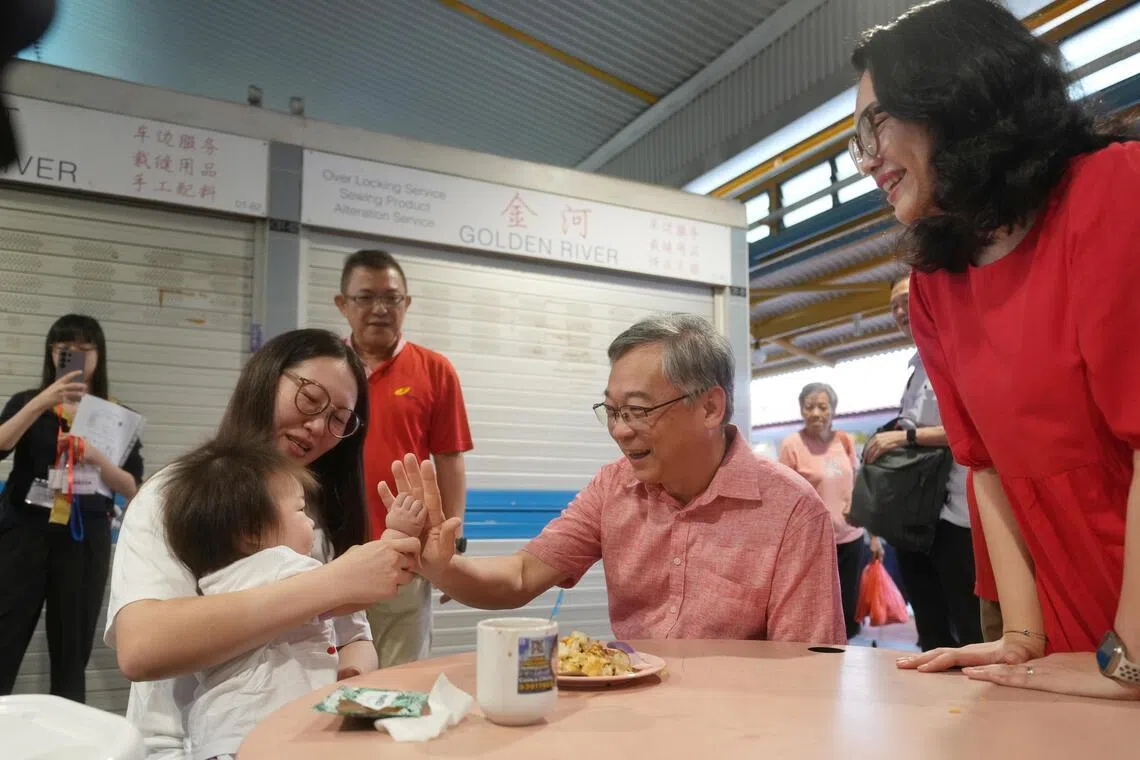 副总理兼贸工部长颜金勇（右二）星期天走访凤山小贩中心与居民交流时，举手与一名女童击掌。右一为负责凤山区事务的东海岸集选区议员何礼娜。（谢智扬摄）