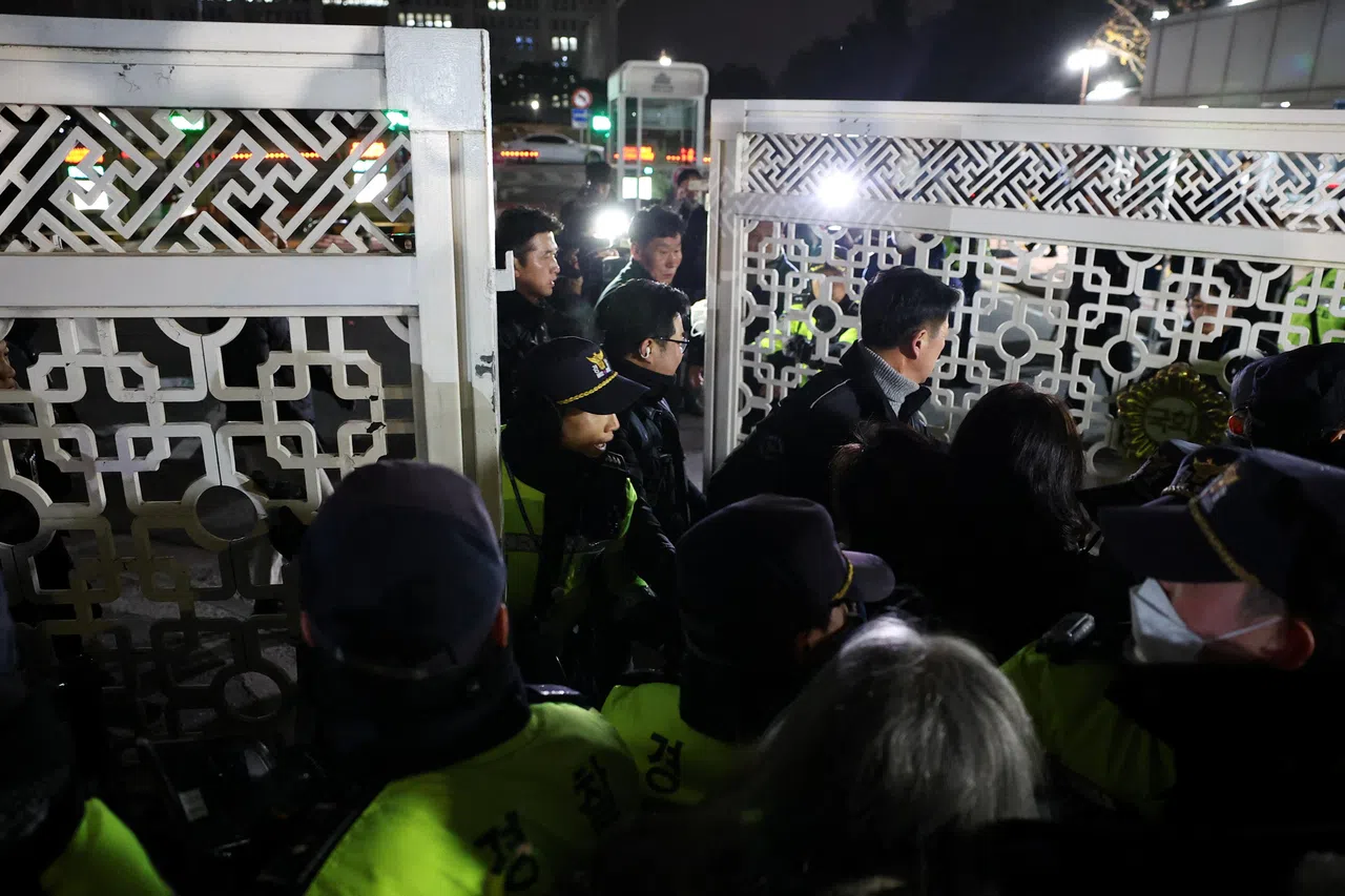 韩国国会大厦外聚集了国会议员和民众，警员在大门外驻守。（路透社）