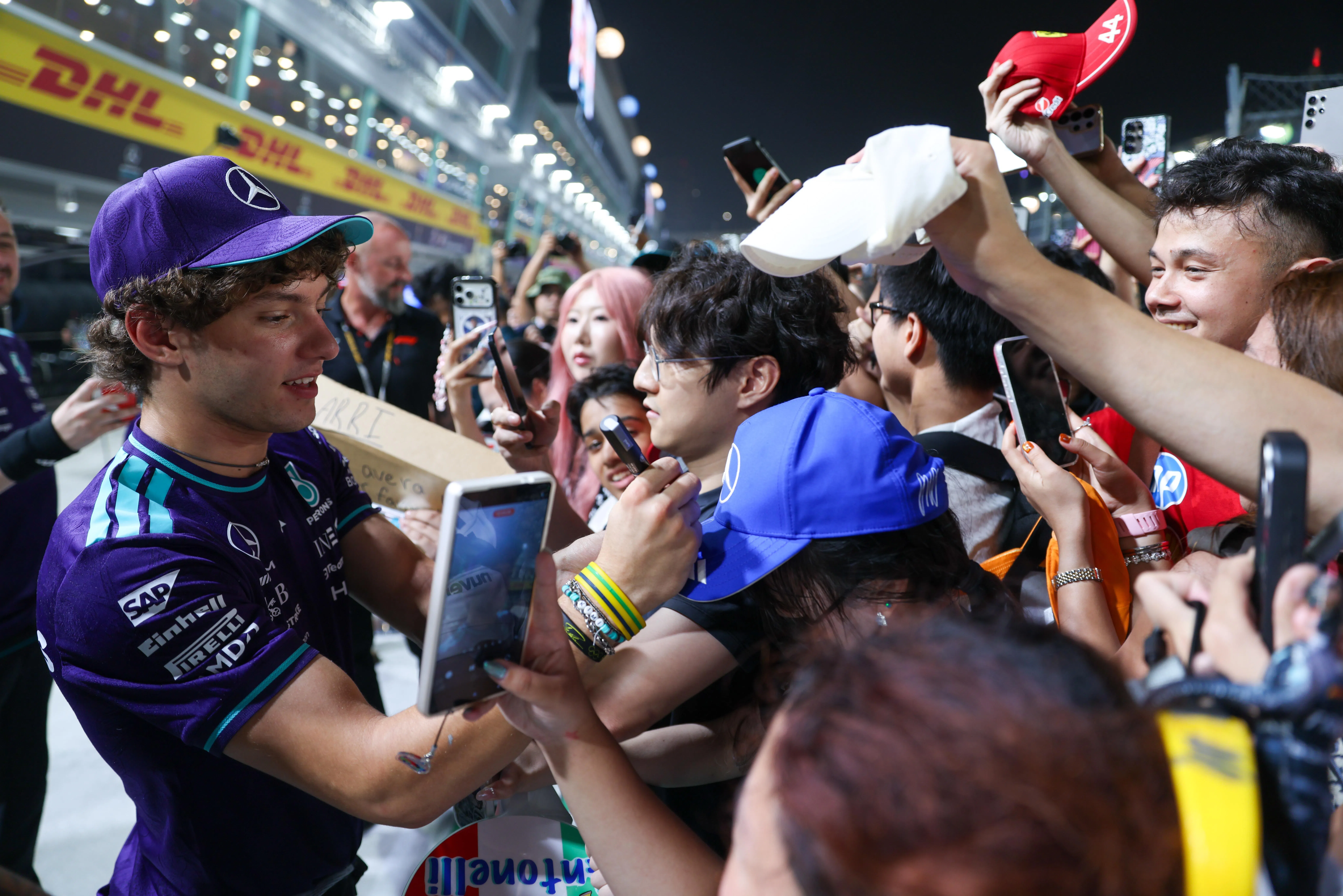 F1维修区通道体验（Pit Lane Walk）让宾客近距离观看车队车房，也有机会遇见车手和获车队邀请的名人。运气好的话，车手还会来到粉丝面前互动。图为本赛季争冠热门、马赛地（Mercedes）车手基米·安东内利（Kimi Antonelli）在新加坡大奖赛正赛前为粉丝签名。（白艳琳摄）