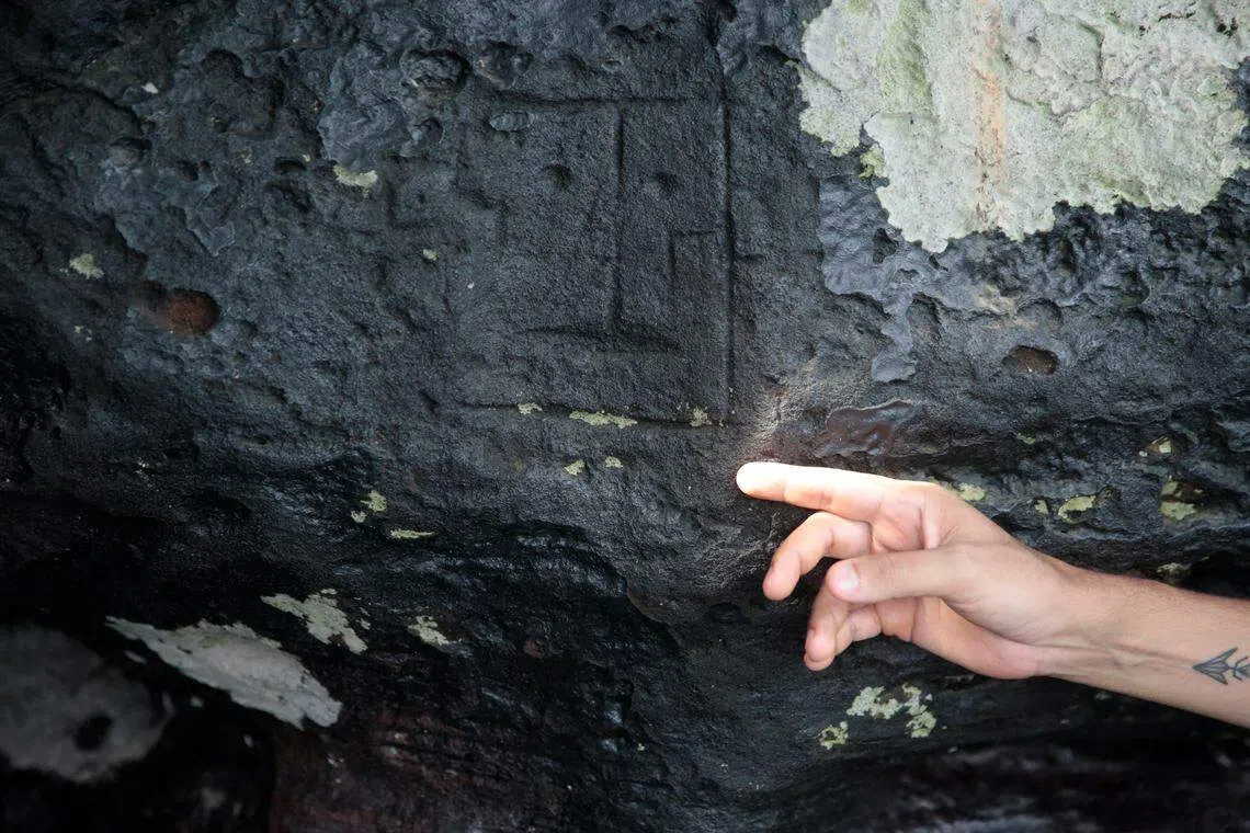 公共卫生与医学研究所（IPHAM）考古学家奥利维拉指着岩石上某处人脸石刻。（路透社）