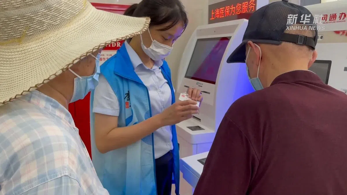 在上海市徐汇区康健街道社区事务受理服务中心，志愿者帮助老人操作申领“离线码”。（新华社）