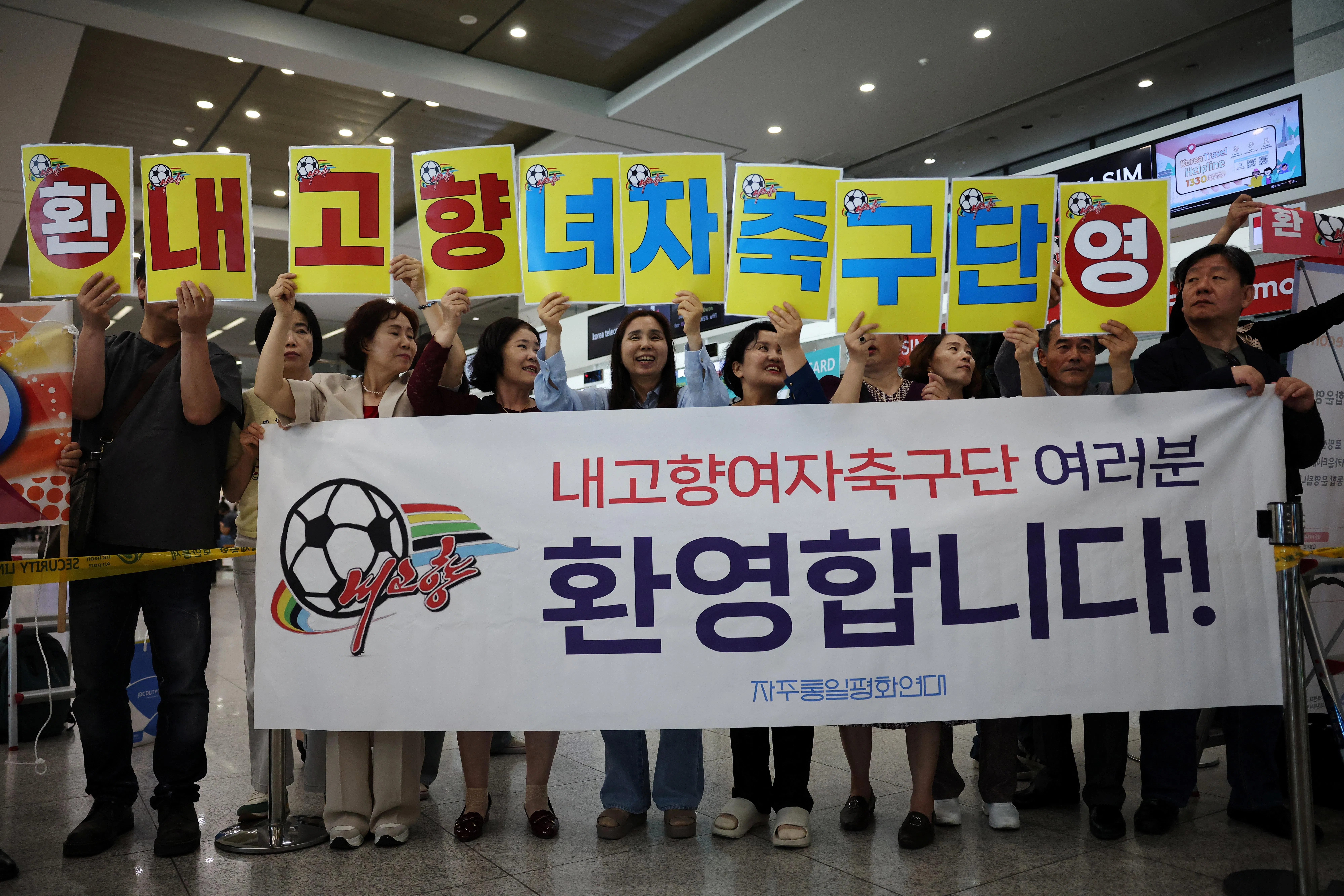 韩国民间团体准备横幅和卡牌，欢迎朝鲜我故乡足球队抵达。（路透社）