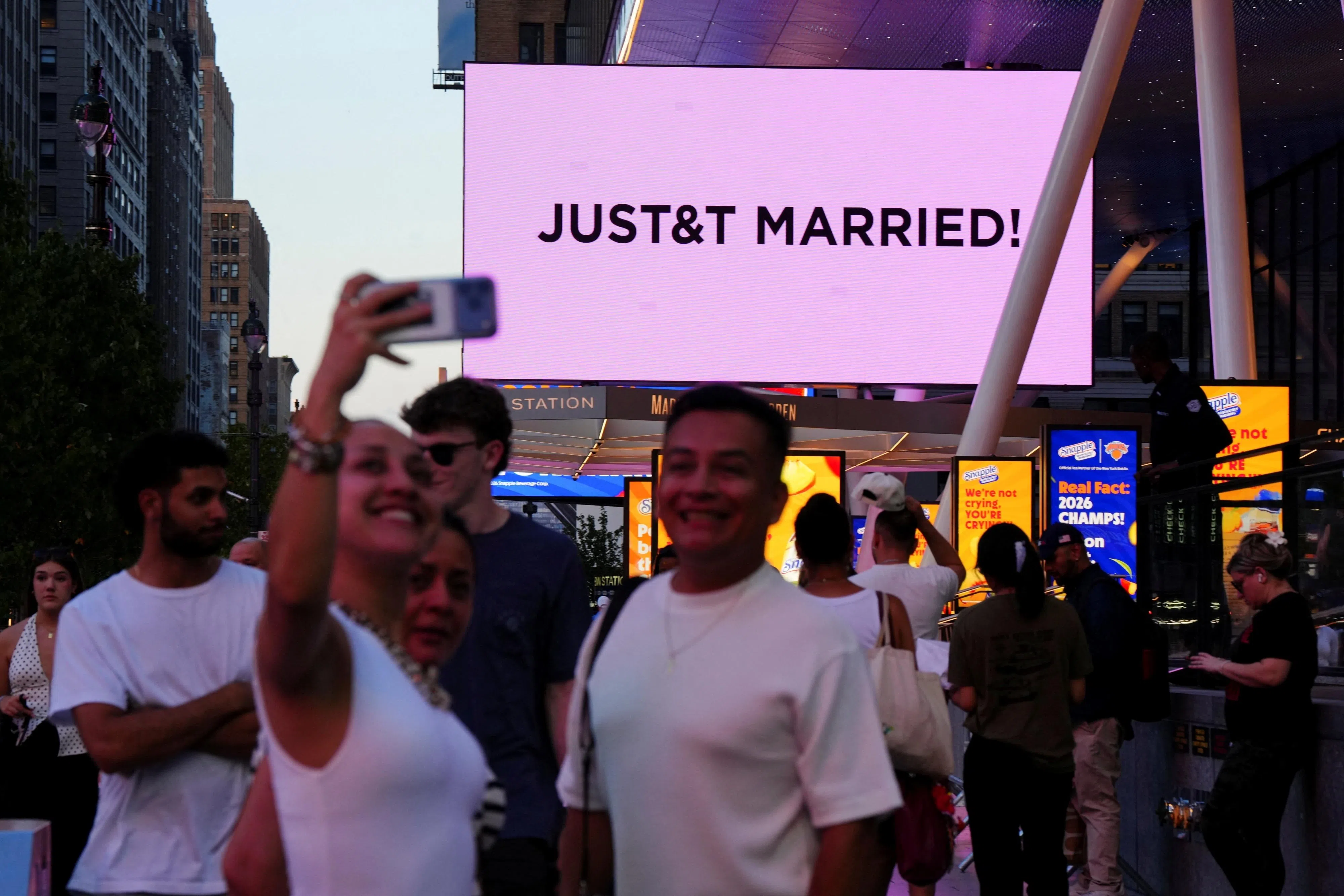 Swift和Kelce在纽约结婚，麦迪逊广场花园的大屏幕显示“JUST&T MARRIED”字样，吸引民众把握机会自拍打卡。（路透社）