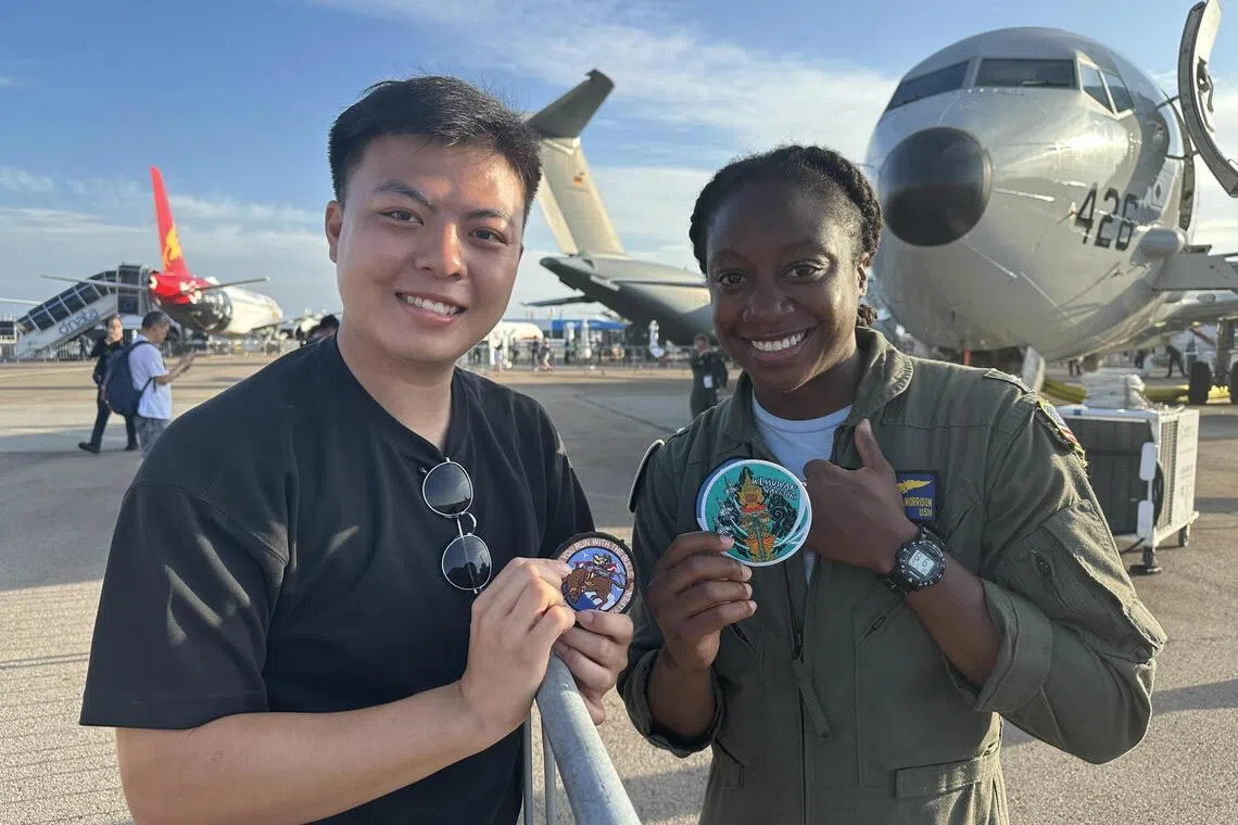 新加坡空军部队工程师陈自德（左）在航空展上，与美军人员交流并交换臂章。他说，每枚臂章都代表个人历练与努力，在国际展会交换臂章是常见的军中传统。（林煇智摄）