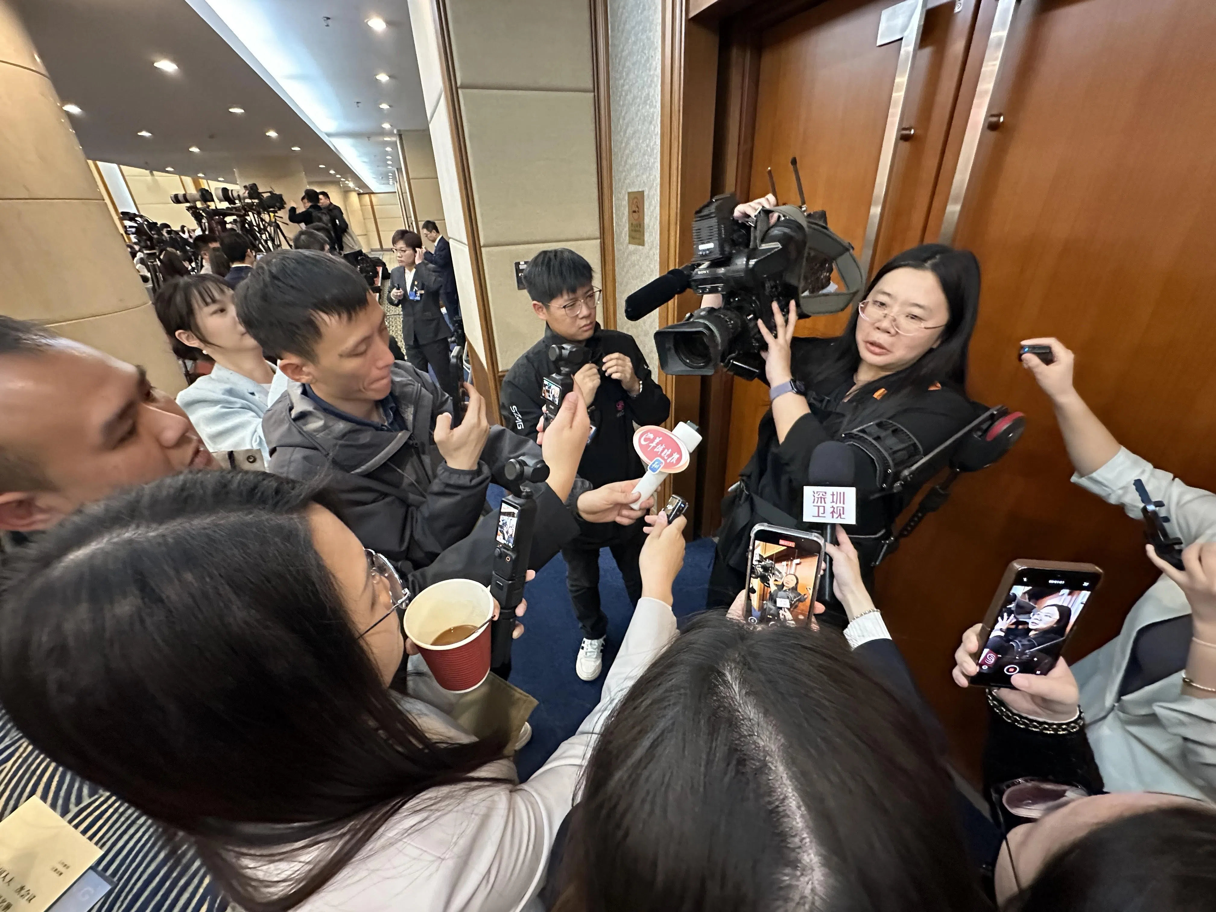 在中国全国人大会议广东省代表团星期四（3月6日）的开放活动上，记者轮流试穿外骨骼机器人。图为试穿机器人的记者被同行围观。（林煇智摄）