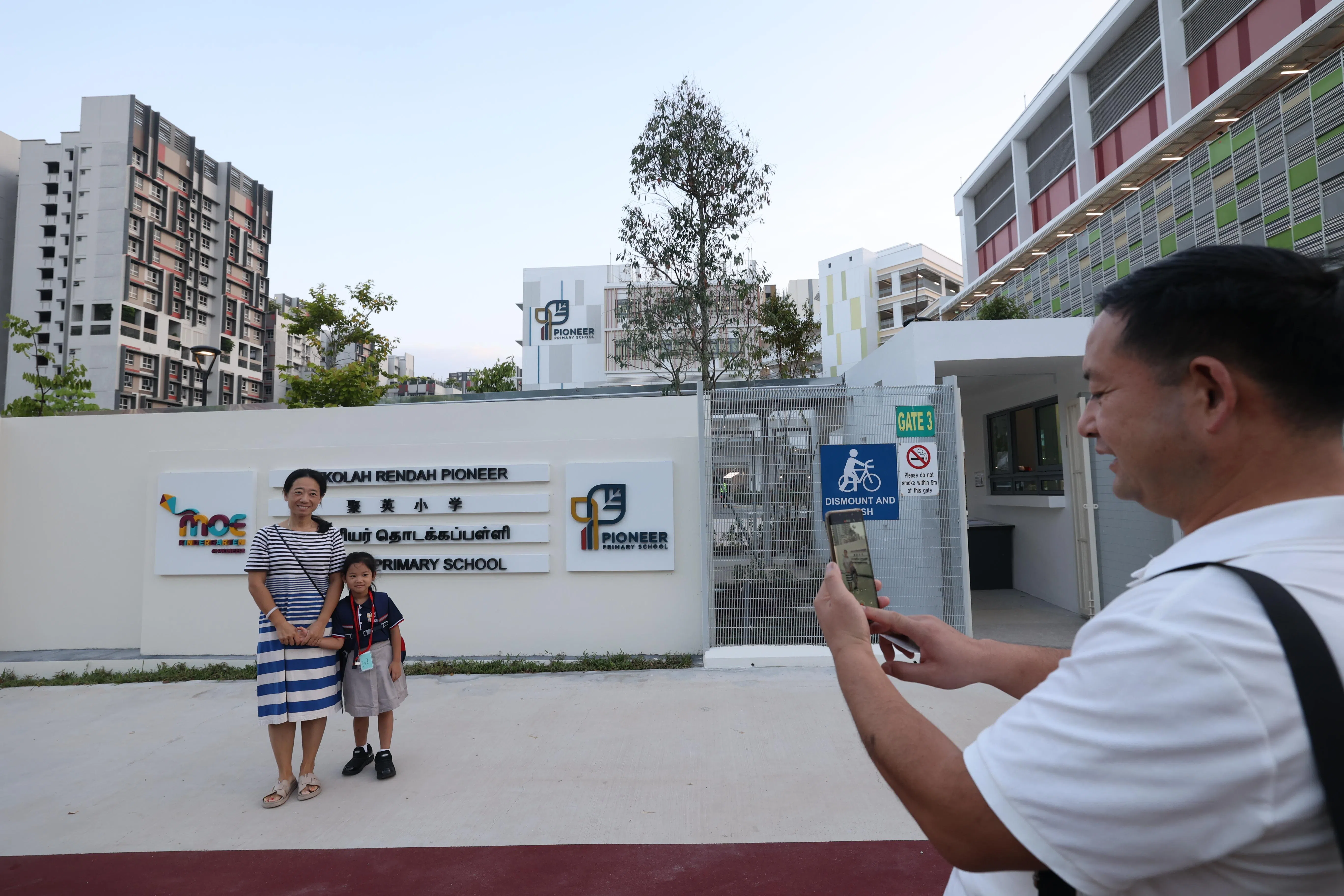 孩子即将开始小学生涯，家长一大早就陪伴孩子上学，在校门口打卡留念。（邝启聪摄）