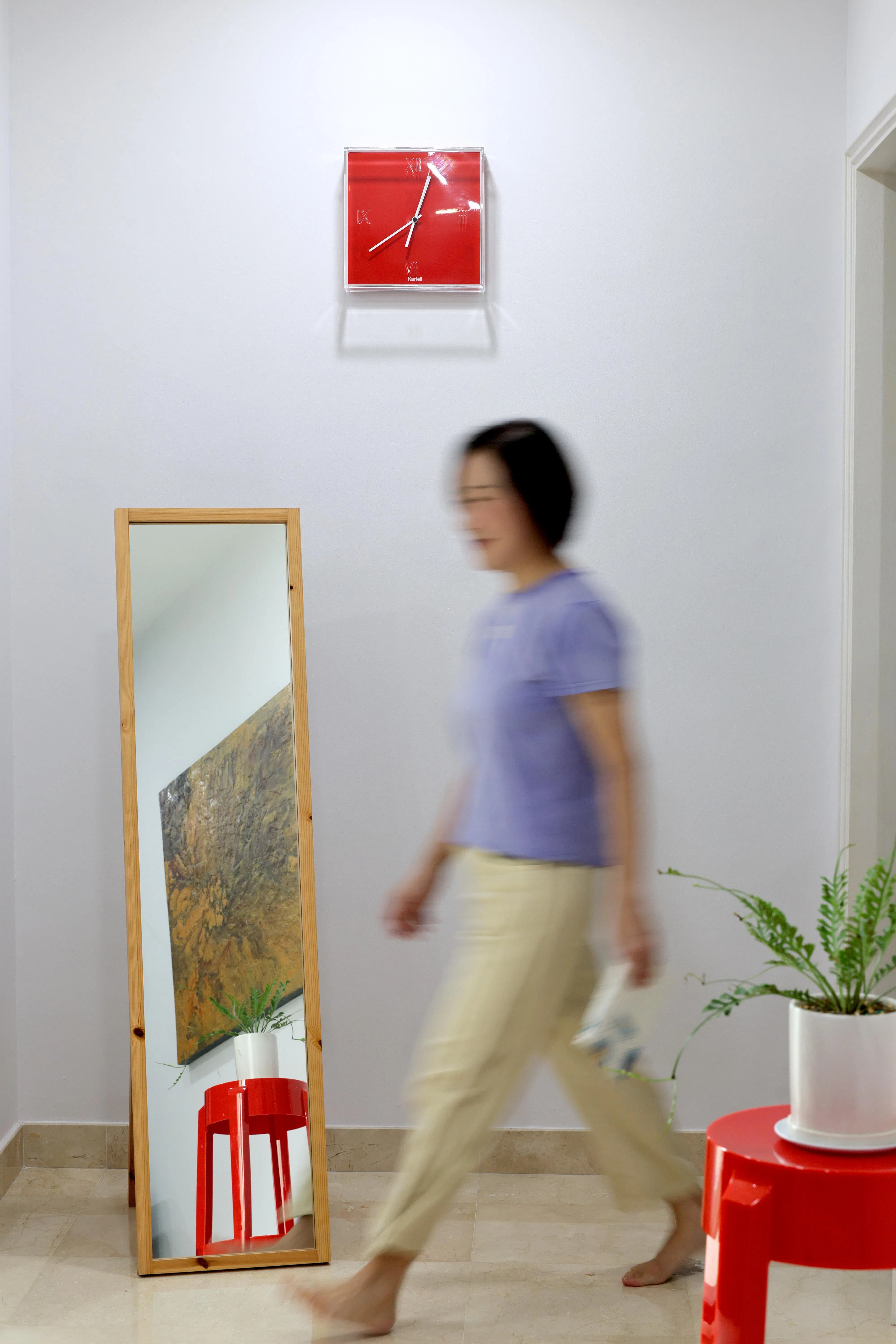 林安娜偏爱有设计感的家具，客厅里的艳红凳子与壁钟，为简约空间添上亮色。（龙国雄摄）