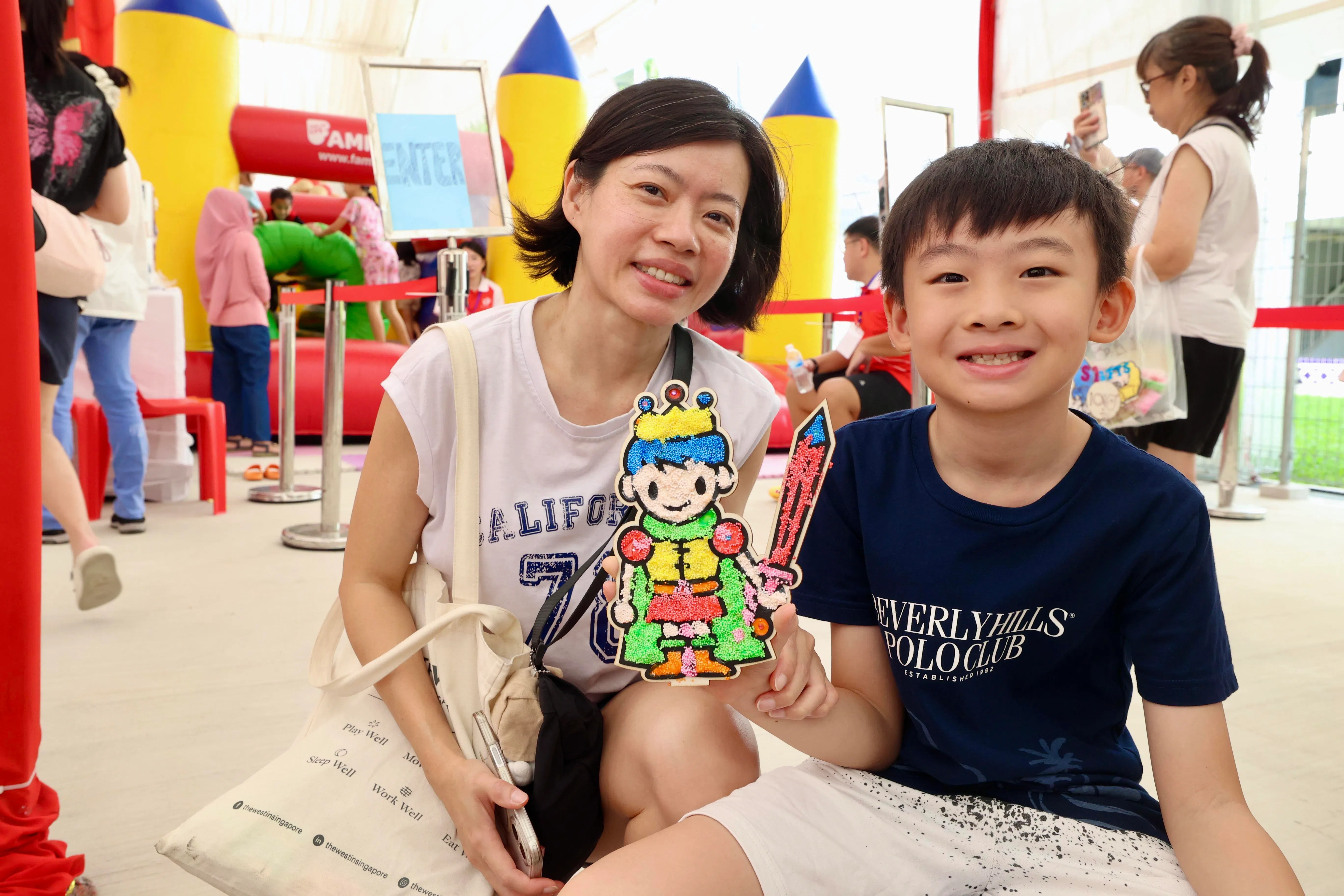 46岁的义顺居民李凤玲带着10岁的儿子李示铉到场参与PLAY@NeeSoon活动，他们报名了机器人工作坊。在等待工作坊开始前，李示铉动手做了一个可爱的小手工。妈妈李凤玲说，现代孩子在家总是用手机和电脑打游戏，她希望孩子发展其他兴趣，不要整天只是盯着屏幕。（邝启聪摄）