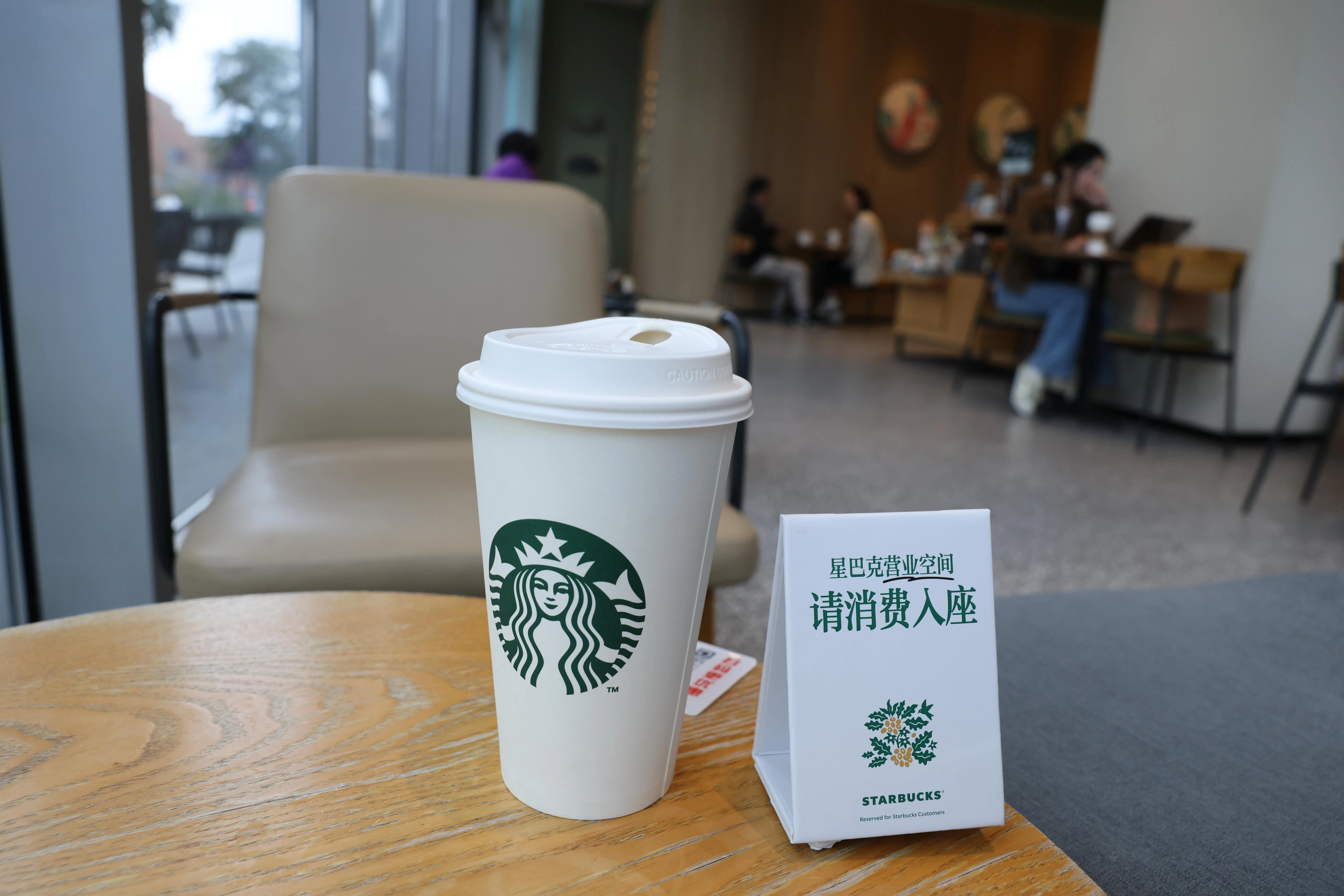 A Starbucks store in Chengdu’s Hi-tech Industrial Development Zone in Sichuan prominently displays a sign asking customers to make a purchase before taking a seat on 22 October, the day the chain introduced the policy across mainland China.（China News Service）