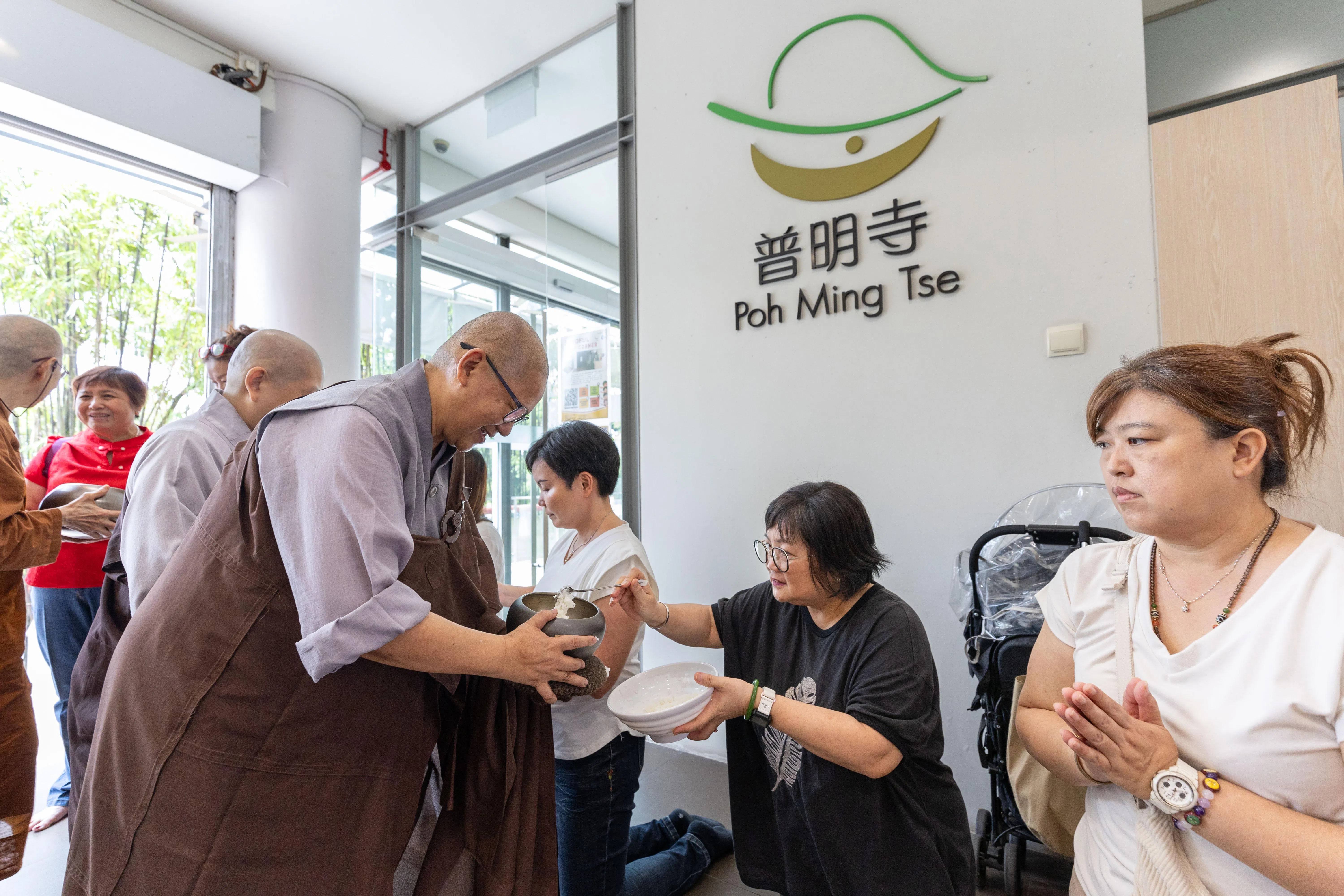 释法巽法师（前排左一）在普明寺举办的室内托钵活动上，接受信徒的供养。（普明寺提供）