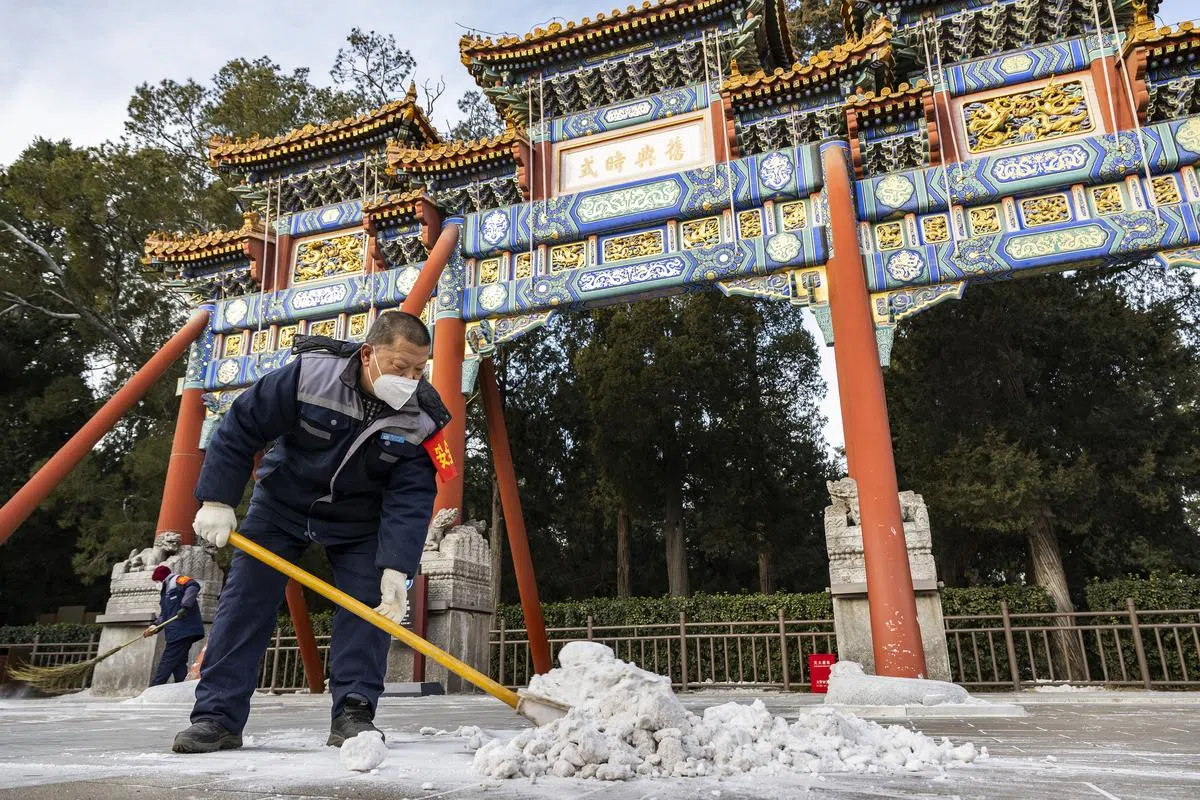 工作人员星期一（1月23日）在北京清理景山公园寿皇殿前的地面积雪。（中新社）