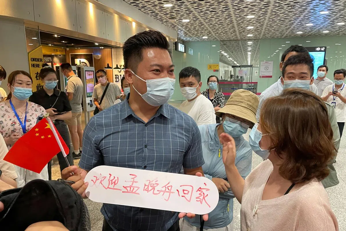 有民众手举“欢迎孟晚舟回家”的标语、（路透社）
