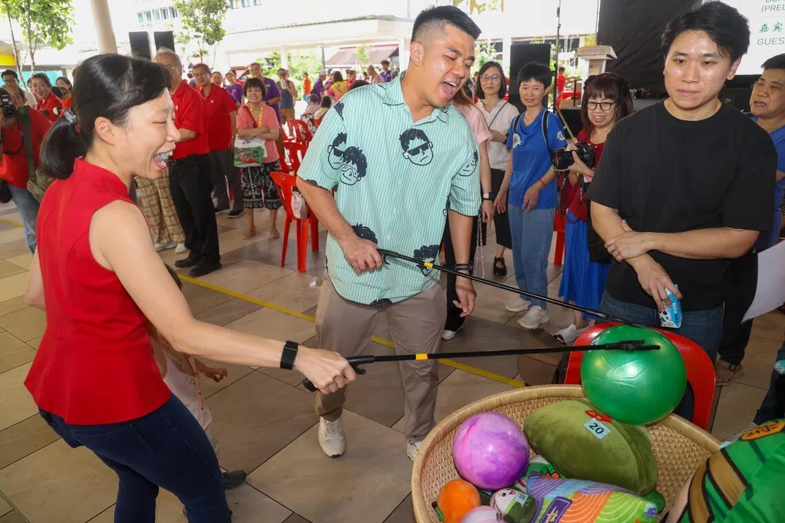 数码发展及新闻部兼教育部政务部长刘洁敏（左）以主宾身份出席端午嘉年华，并与碧山—大巴窑集选区议员蔡引舟（中）一同参与接力夹粽子游戏。（吴先邦摄）