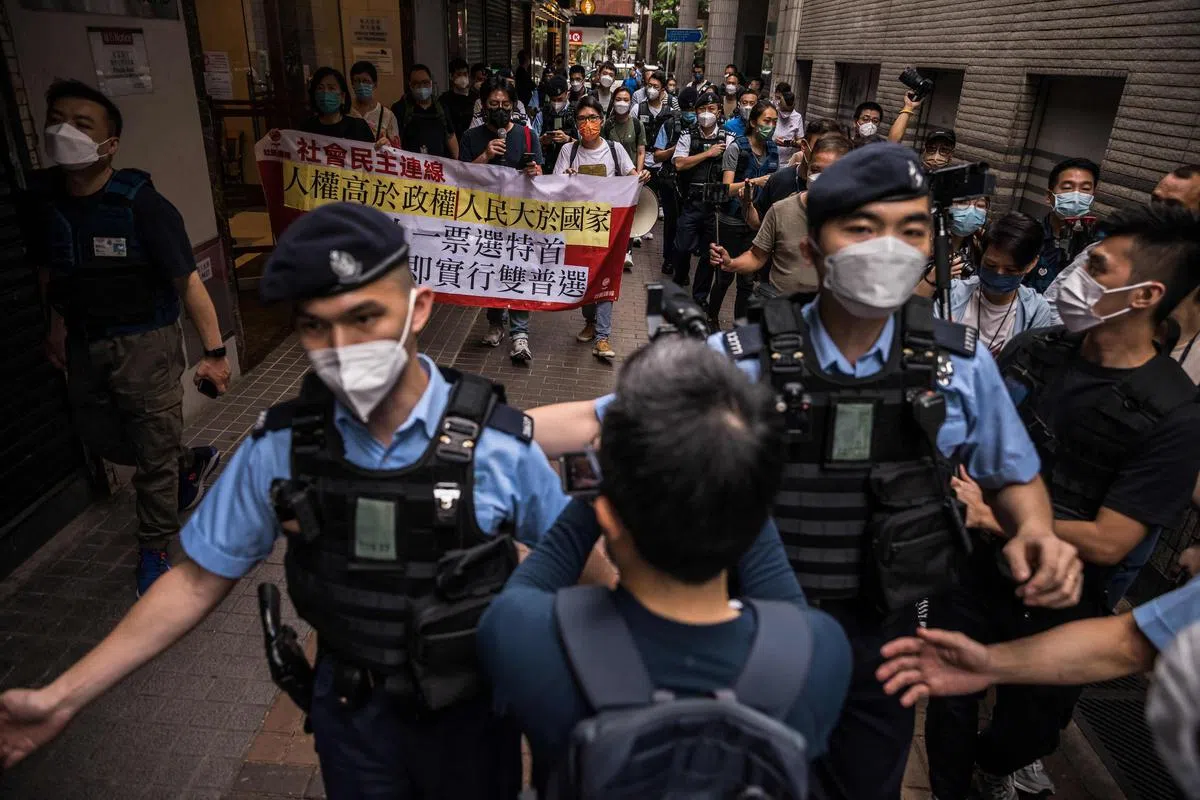 香港泛民主派组织“社会民主连线”三名成员今早上街示威，要求香港实行双普选。香港警员在附近驻守。（法新社）