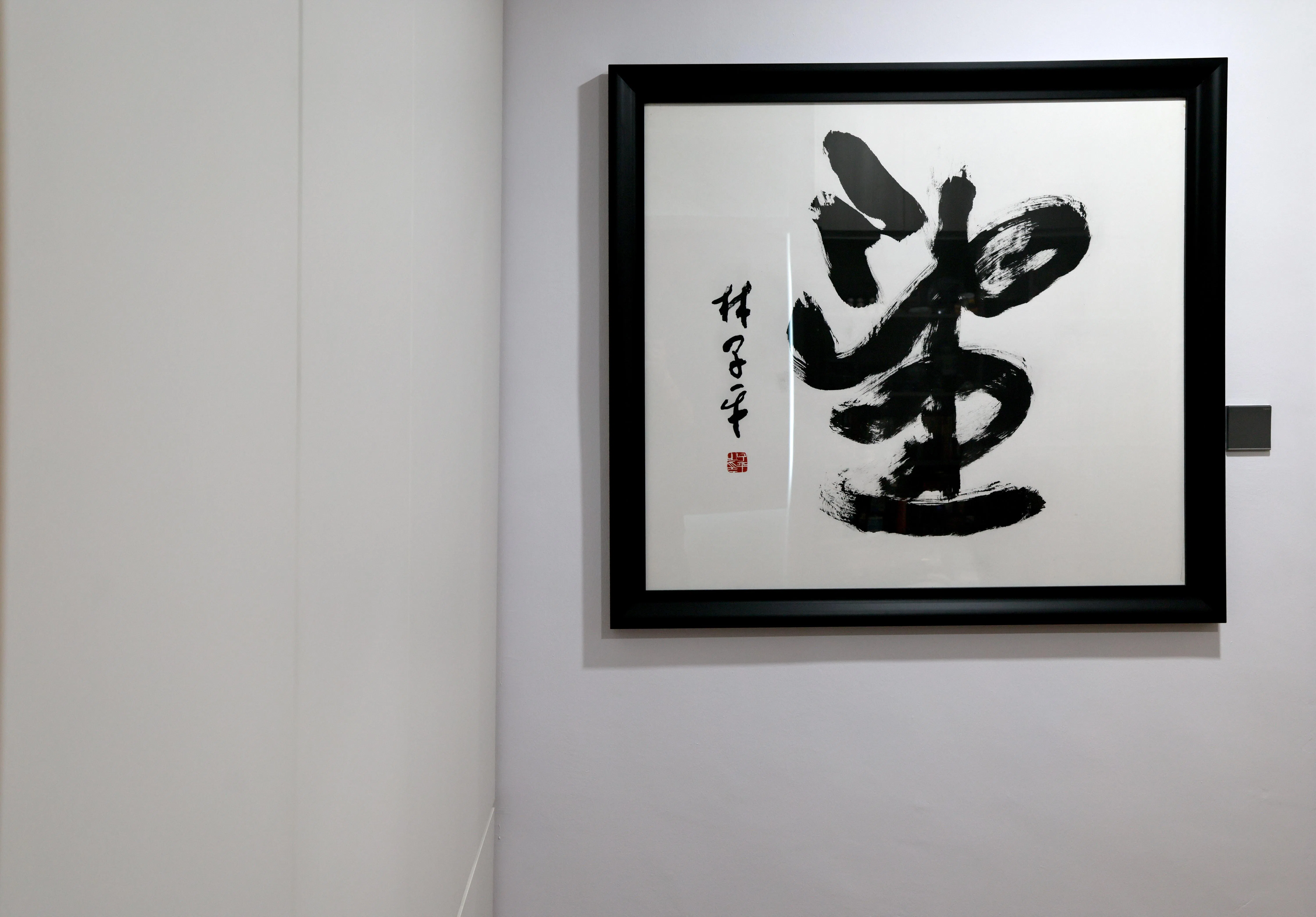 书房墙上挂着已故本地画家林子平2018年赠林安娜的“望”字画。（龙国雄摄）