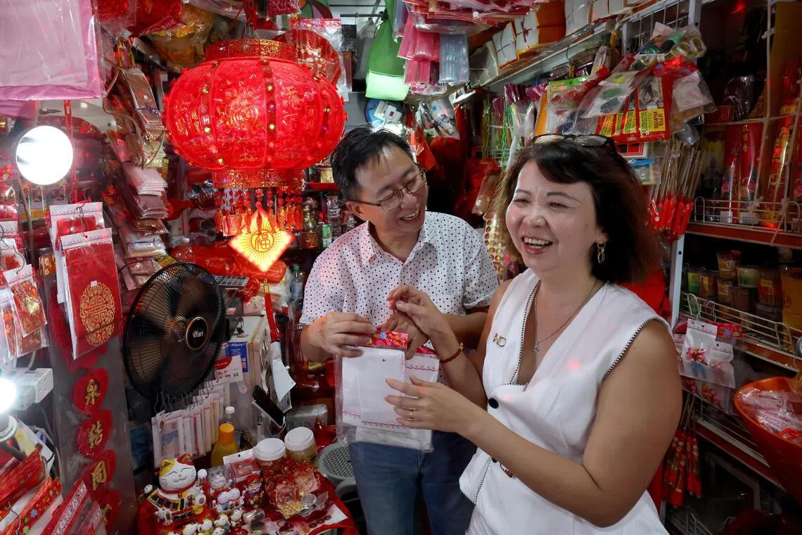 宏丽不仅售卖婚庆用品、经营批发，加冷峇鲁门店还会因应农历新年、清明等节庆调整货品。詹维宏（左）也为顾客提供看风水、择日等服务。（梁麒麟摄）