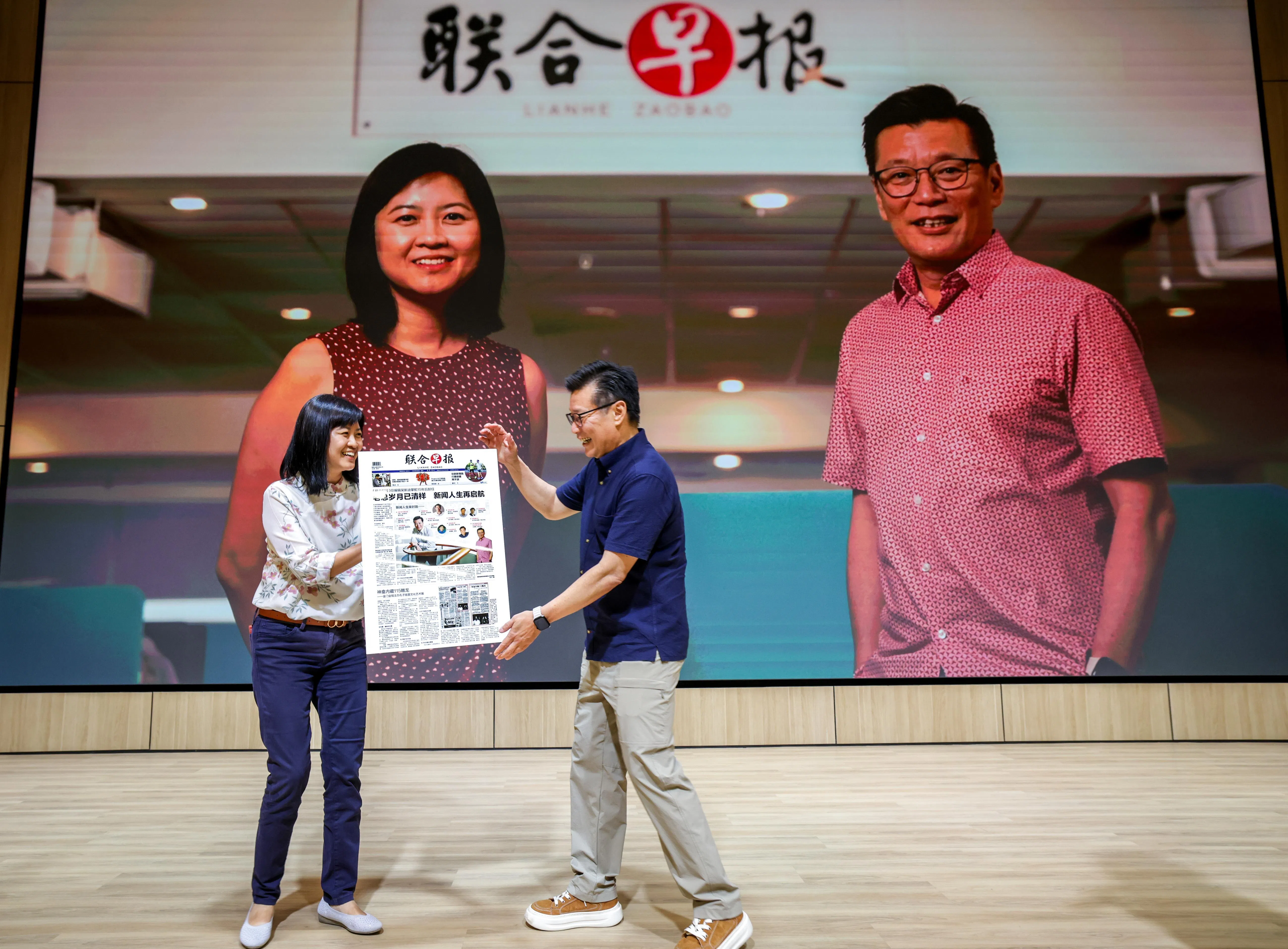 《联合早报》新任总编辑洪奕婷（左）为吴新迪（右）送上的荣休礼物，是一份特别版早报封面，刊登他首篇署名报道，并记录他的新闻人生历程。（叶振忠摄）