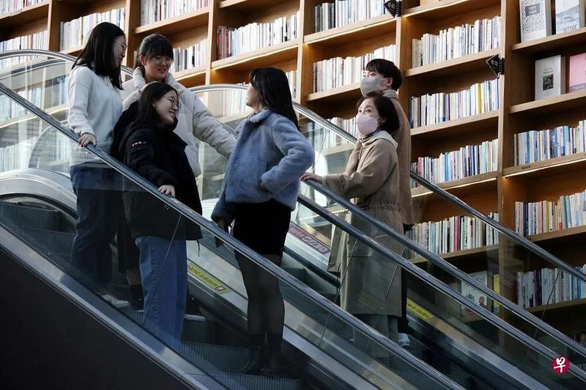 1月30日，韩国解除室内戴口罩令的第一天，首尔一家购物中心内的购物者中，有人选择不戴口罩，有人则继续戴口罩。（路透社）