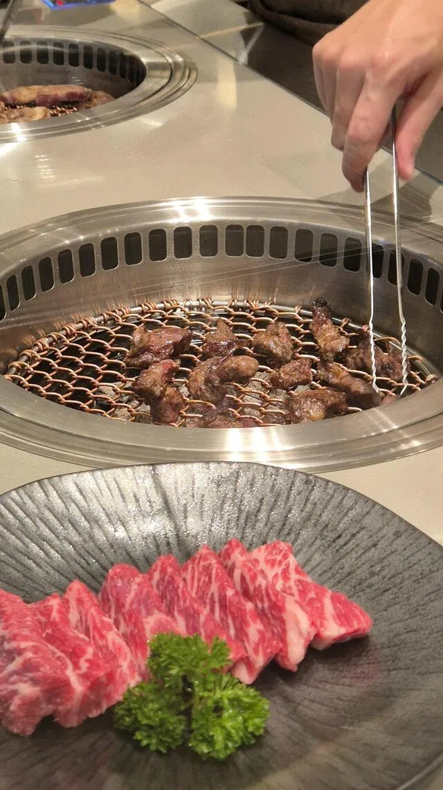 餐馆将烤炉移到餐桌旁，食客可看到服务生在认真地烤肉。（陈爱薇摄）