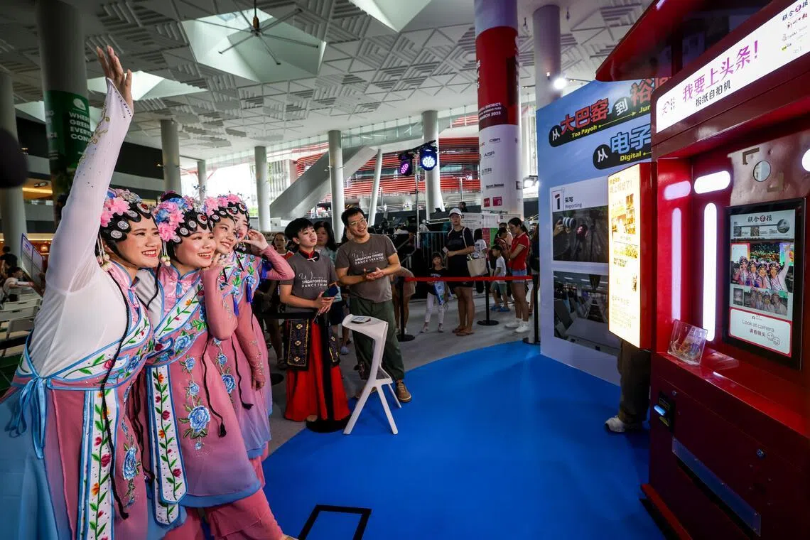 嘉年华活动现场设有媒体体验区、游戏区及合作伙伴展区，吸引了大批公众参与体验。图为华族舞蹈表演者在“我要上头条”互动摊位合影留念。（叶振忠摄）