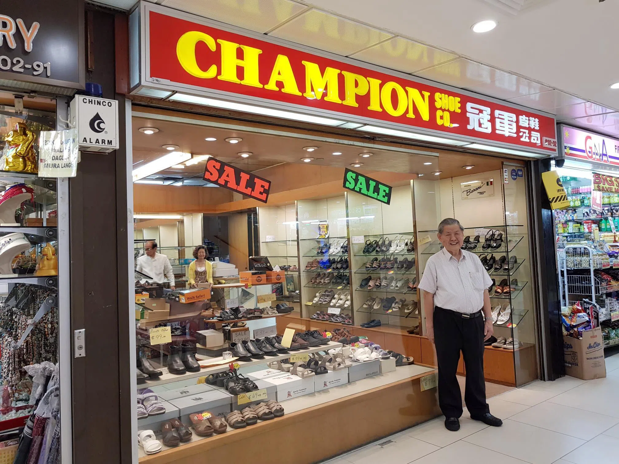 “冠军皮鞋公司”创办人蔡东站在位于幸运商业中心的其中一家分店外。照片拍摄于2018年8月。（受访者提供）
