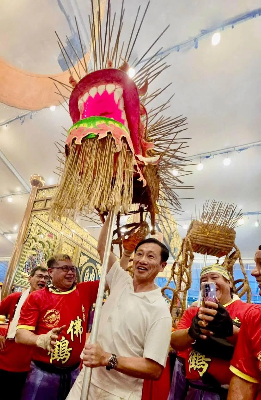 社会政策统筹部长兼保健卫生部长王乙康在龙南殿的九皇爷诞庆典中，抬起稻草火龙，笑言龙头比预想中沉重得多。（取自王乙康脸书）