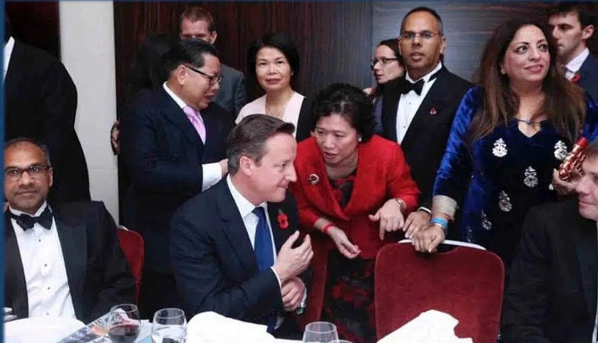 推特上的照片显示，李贞驹在时任英国首相卡梅伦的耳边说话。据《每日邮报》报道，照片摄于2015年的英国“GG2领导力与多元化大奖”（British GG2 leadership awards）颁奖典礼，李贞驹当时是15年来首位获得该奖的华人。（推特）
