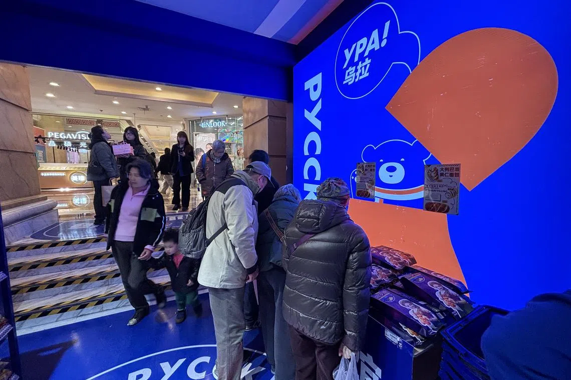 上海俄罗斯商品馆内，一群顾客正在了解店门口陈列的大列巴如何食用。（黎康摄）