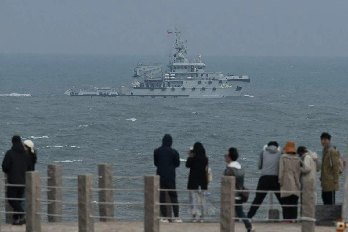 身处身处福建平潭岛的游客看着中国人民解放军一艘拖船星期五（4月7日）驶经台湾海峡。（法新社）